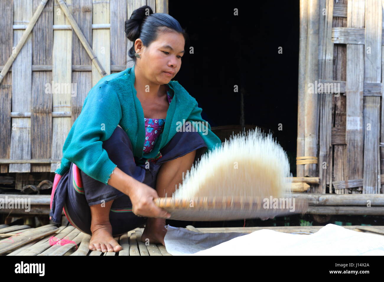 A woman from the Tripura of Tipra ethnic community husking rice infront ...