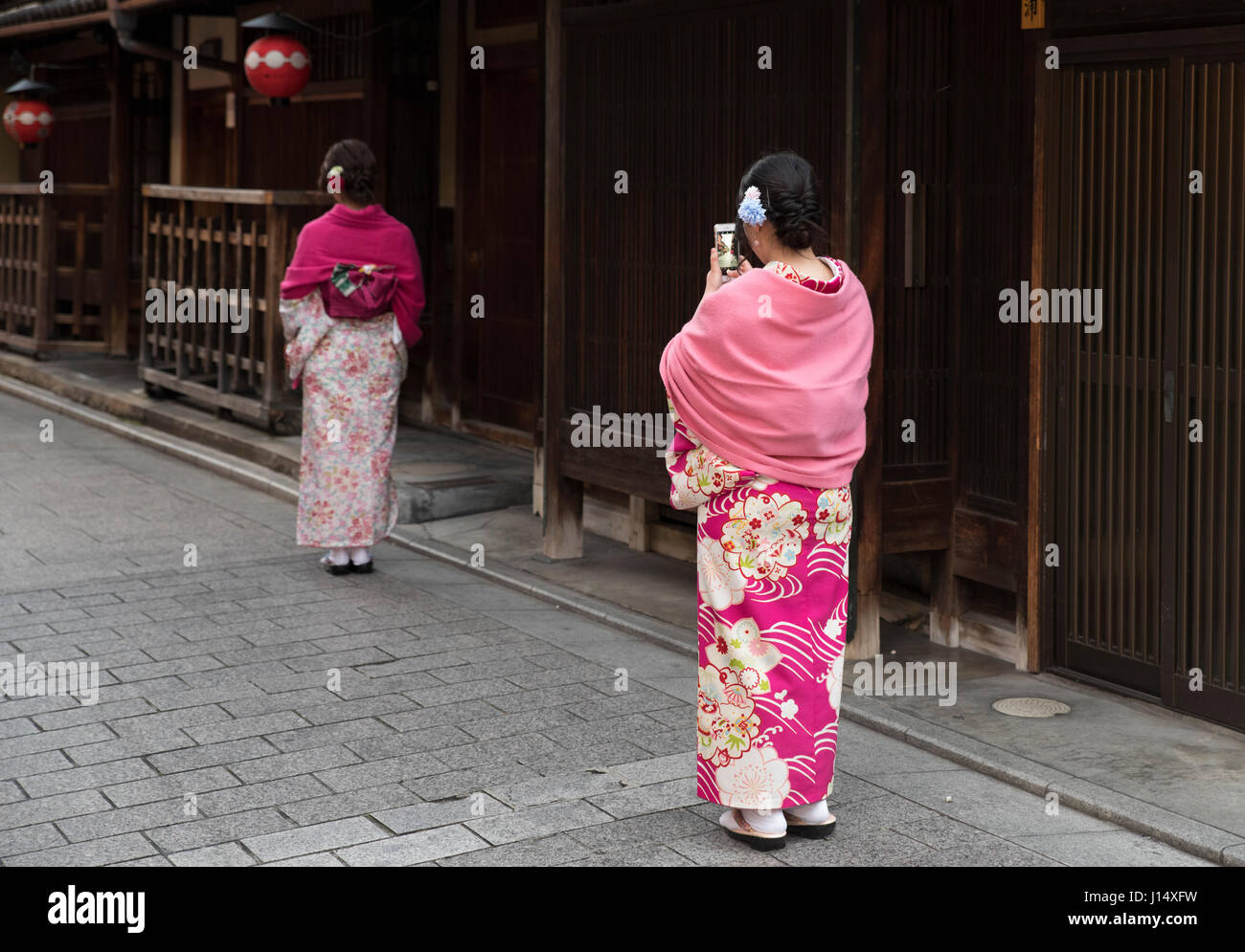 Tourists in kimono pose for iPhone photos in Hanami-koji Street, Gion, Higashiyama, Kyoto, Japan Stock Photo