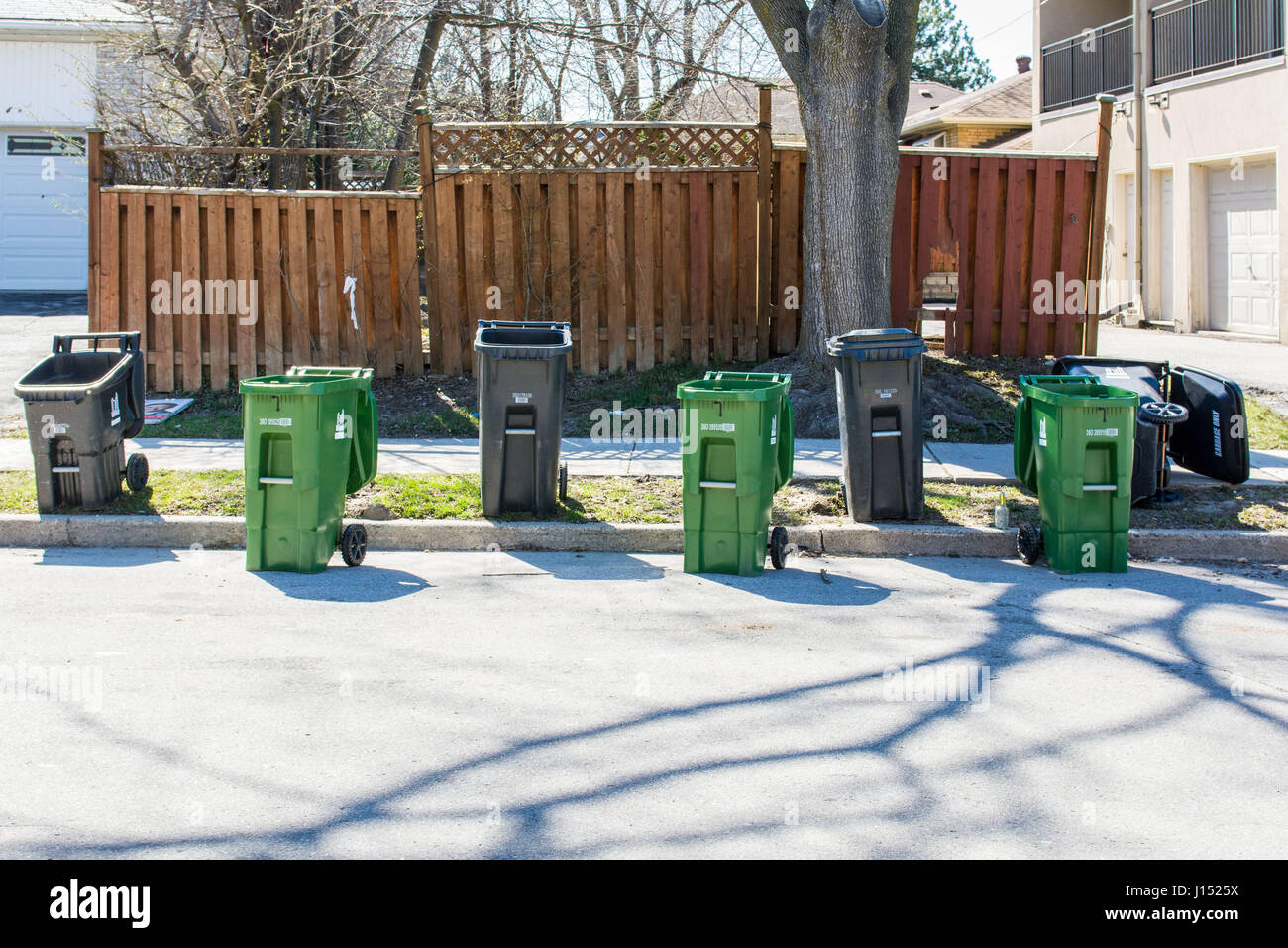 Emptied household green bins and garbage bins are left on the street