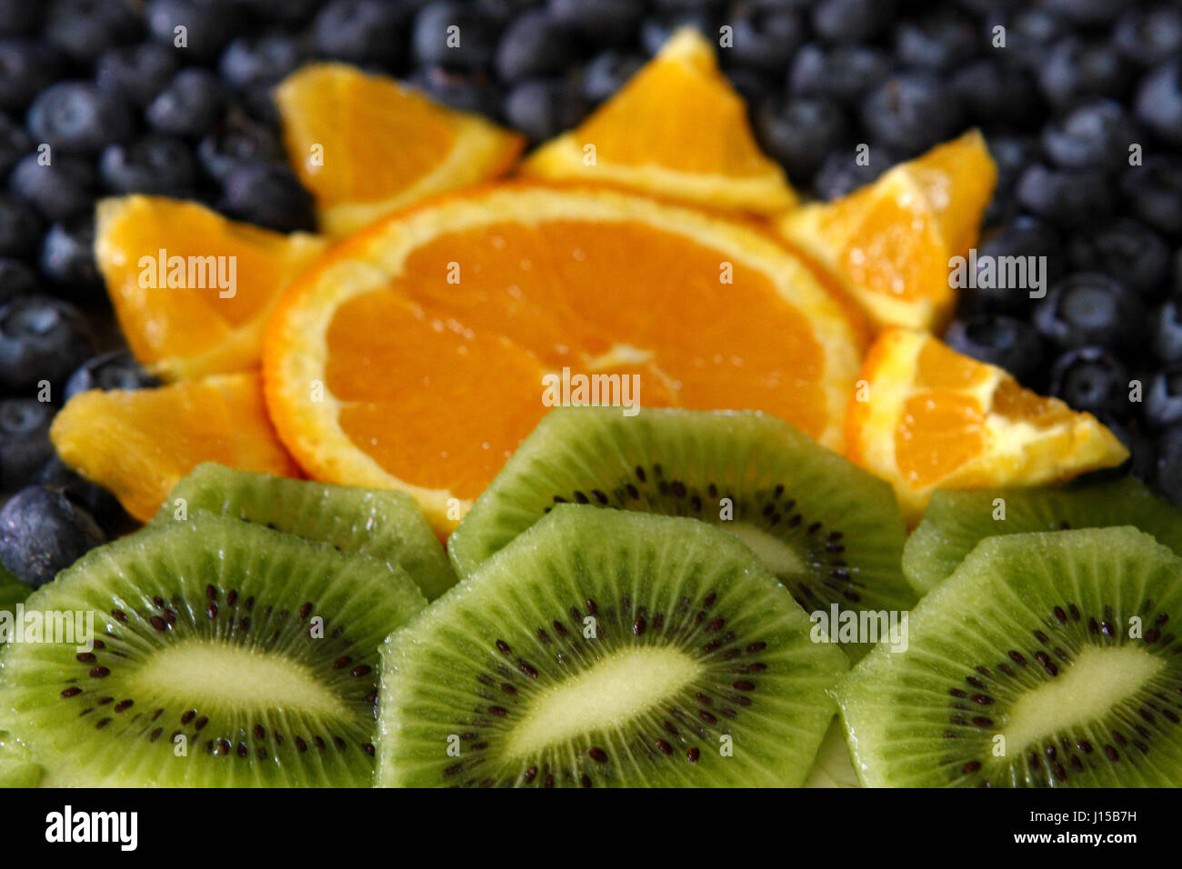 blueberries, kiwis and oranges setup to resemble a sunrise Stock Photo