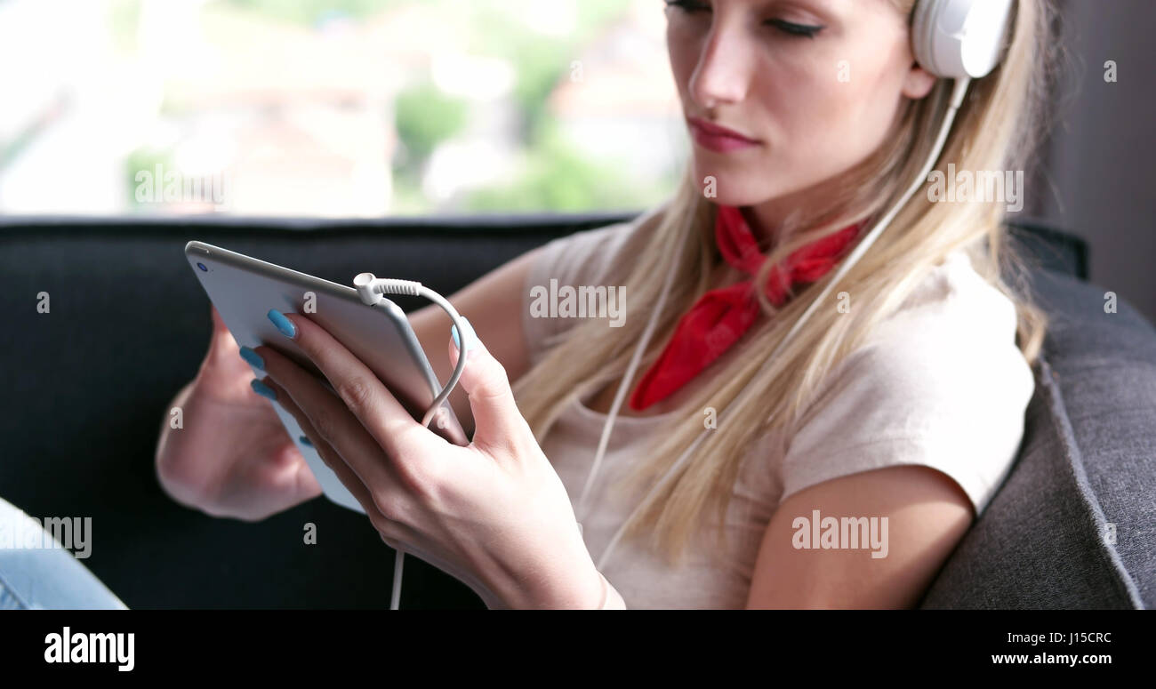 Blonde Woman Sitting On A Sofa Using Her Tablet Stock Photo - Alamy