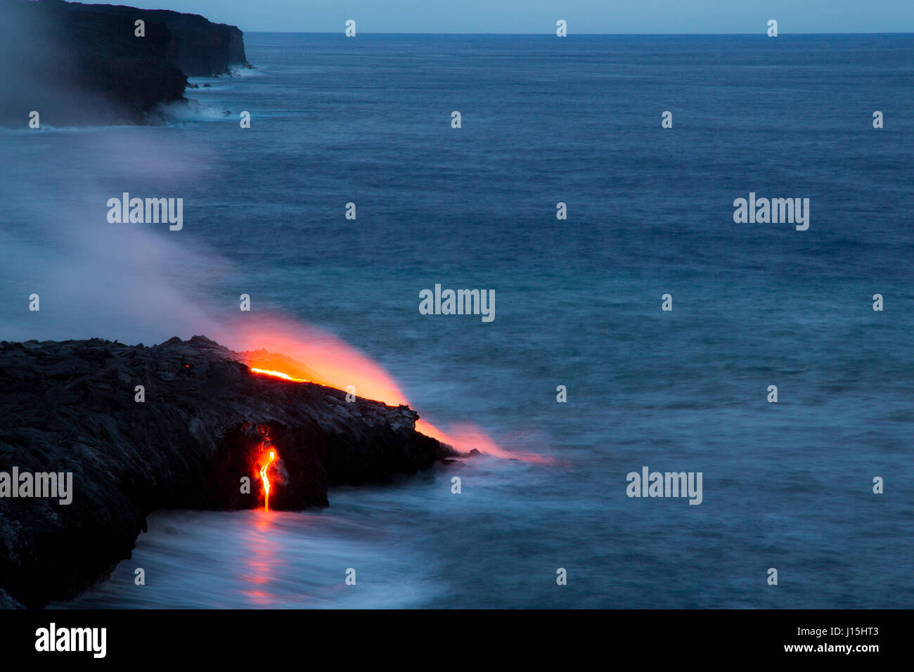 Red glowing lava flowing into the sea in the Hawaii Volcanoes National Park on Big Island, Hawaii, USA. Stock Photo
