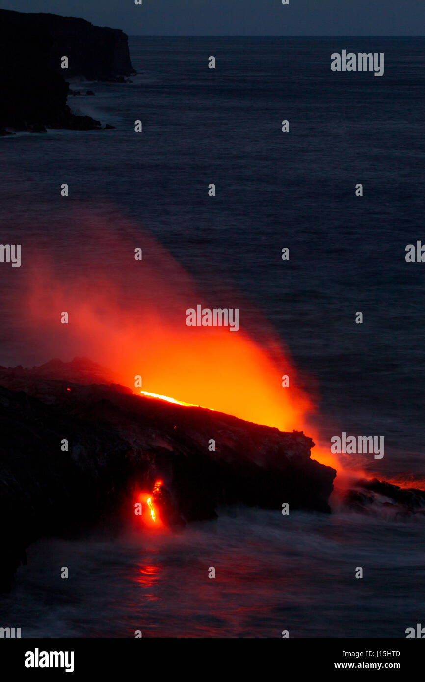 Red glowing lava flowing into the sea in the Hawaii Volcanoes National Park on Big Island, Hawaii, USA. Stock Photo