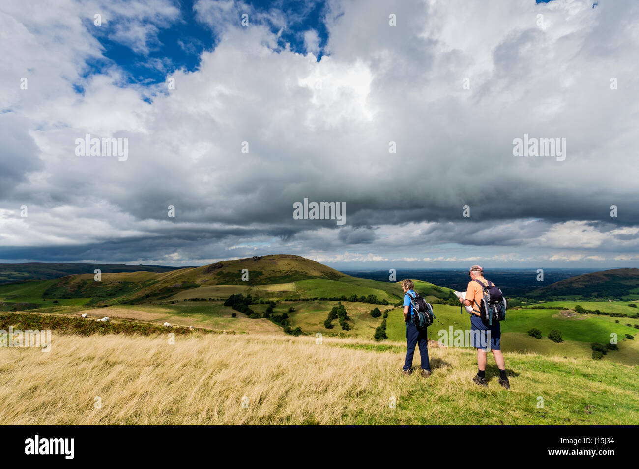 Walkers on Willstone Hill, with Caer Caradoc in the distance, in the Hope Bowdler hills, near Church Stretton, Shropshire, England, UK. Stock Photo