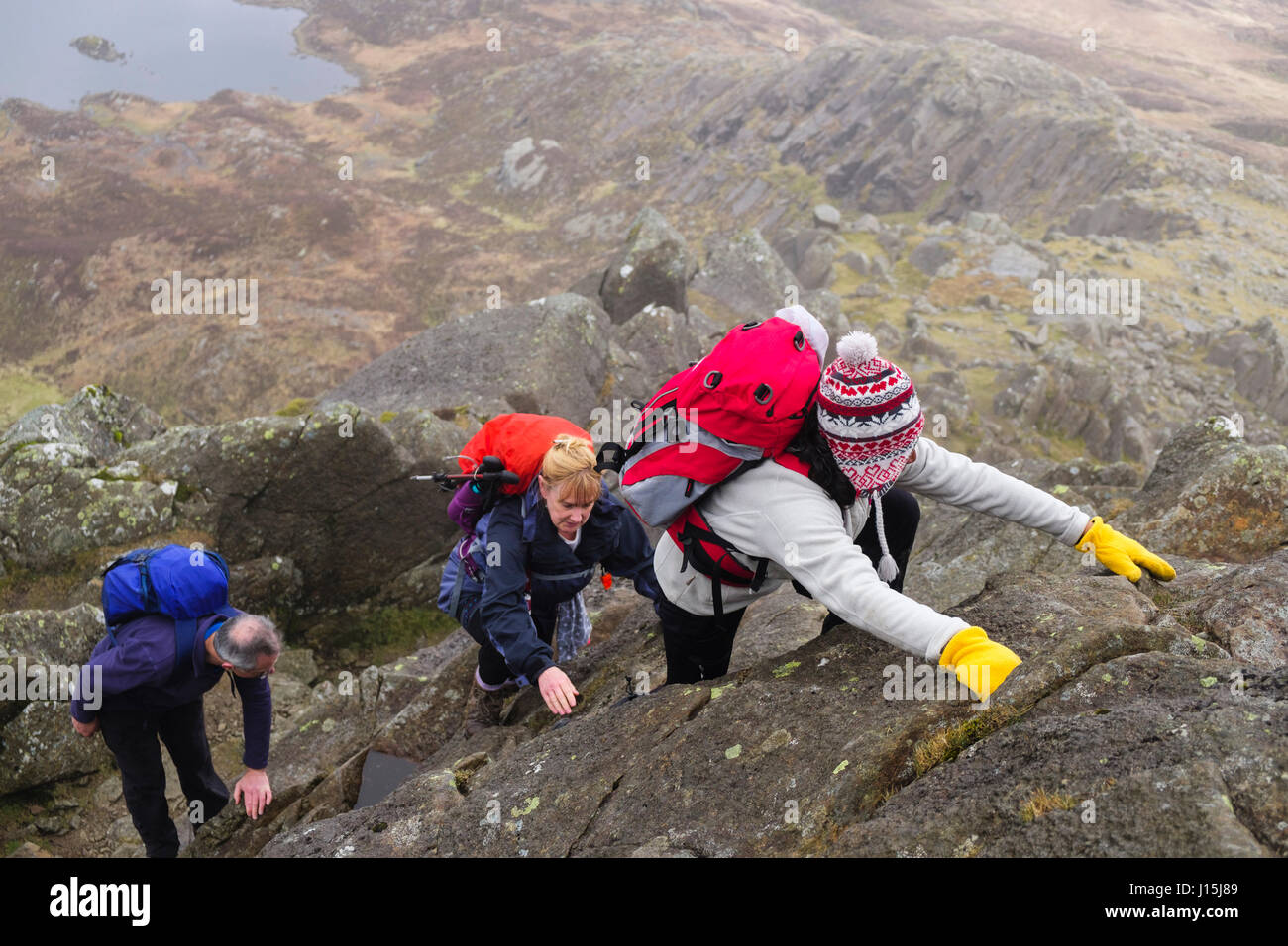 Hikers scrambling up rocks on Daear Ddu east ridge on Carnedd Moel Siabod mountain in Snowdonia National Park mountains. Capel Curig Wales UK Britain Stock Photo