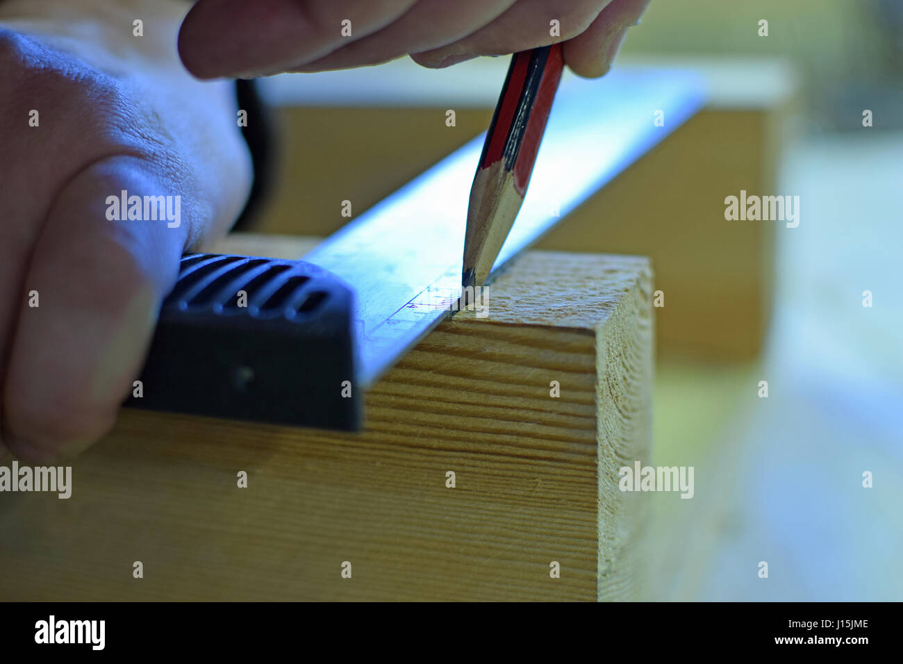 Carpenter marking cutting line to wooden plank. Stock Photo