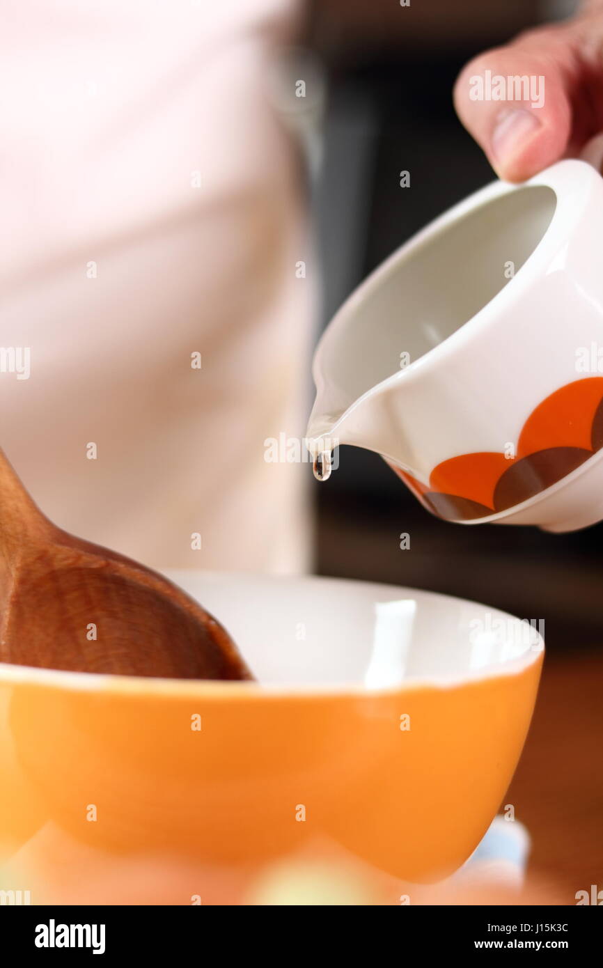 Pouring oil to an egg yolk. Making mayonnaise with a wooden spoon Stock