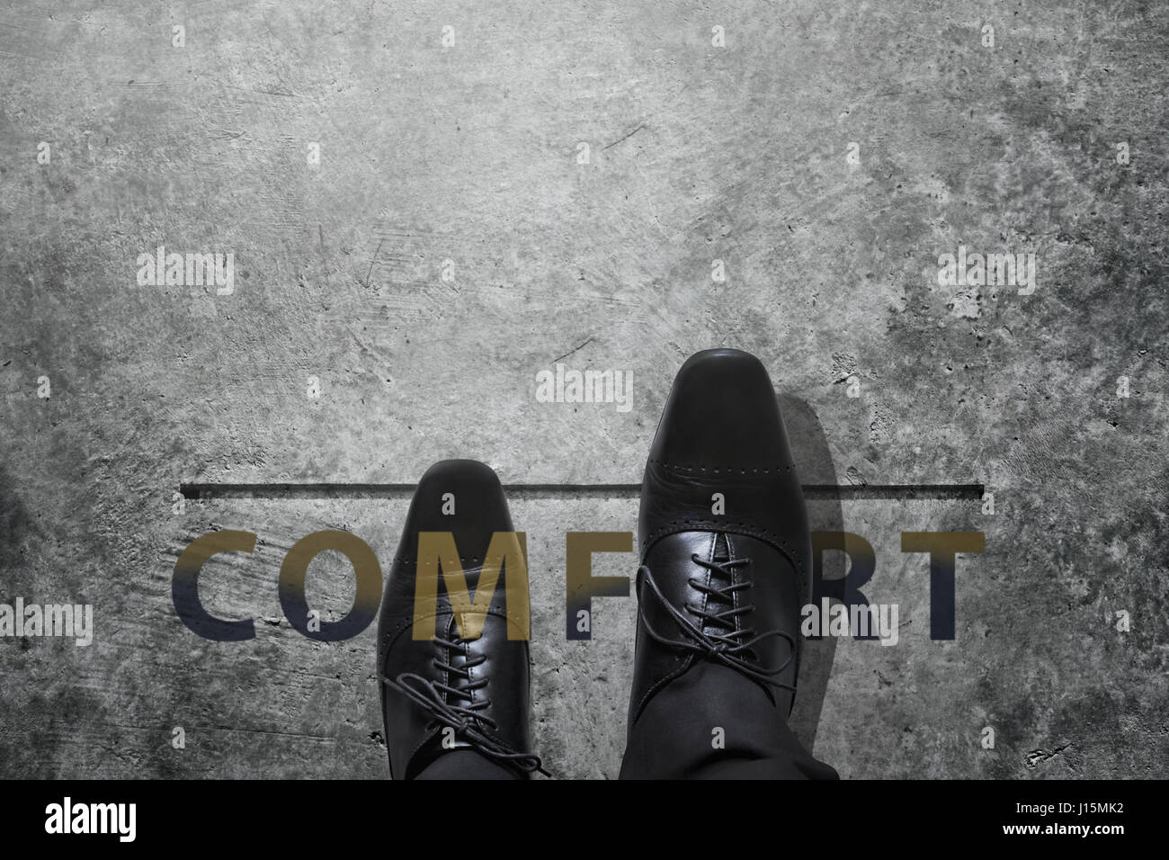 Comfort zone concept, Luxury Businessman step out of his safety boundary, Present by Black Leather shoes over a word and concrete floor, focus on righ Stock Photo