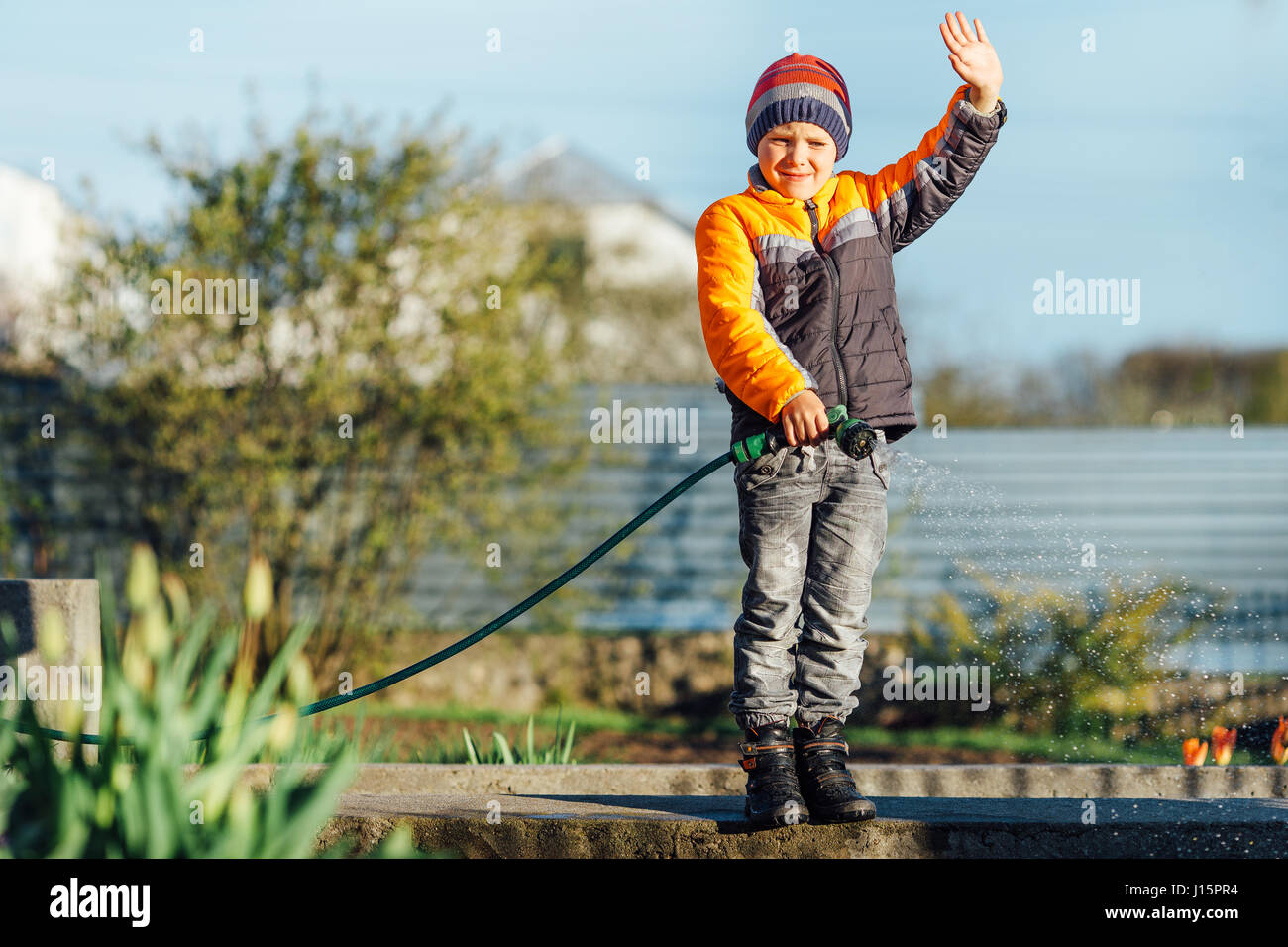 Little boy watering flowers with sunset background Stock Photo