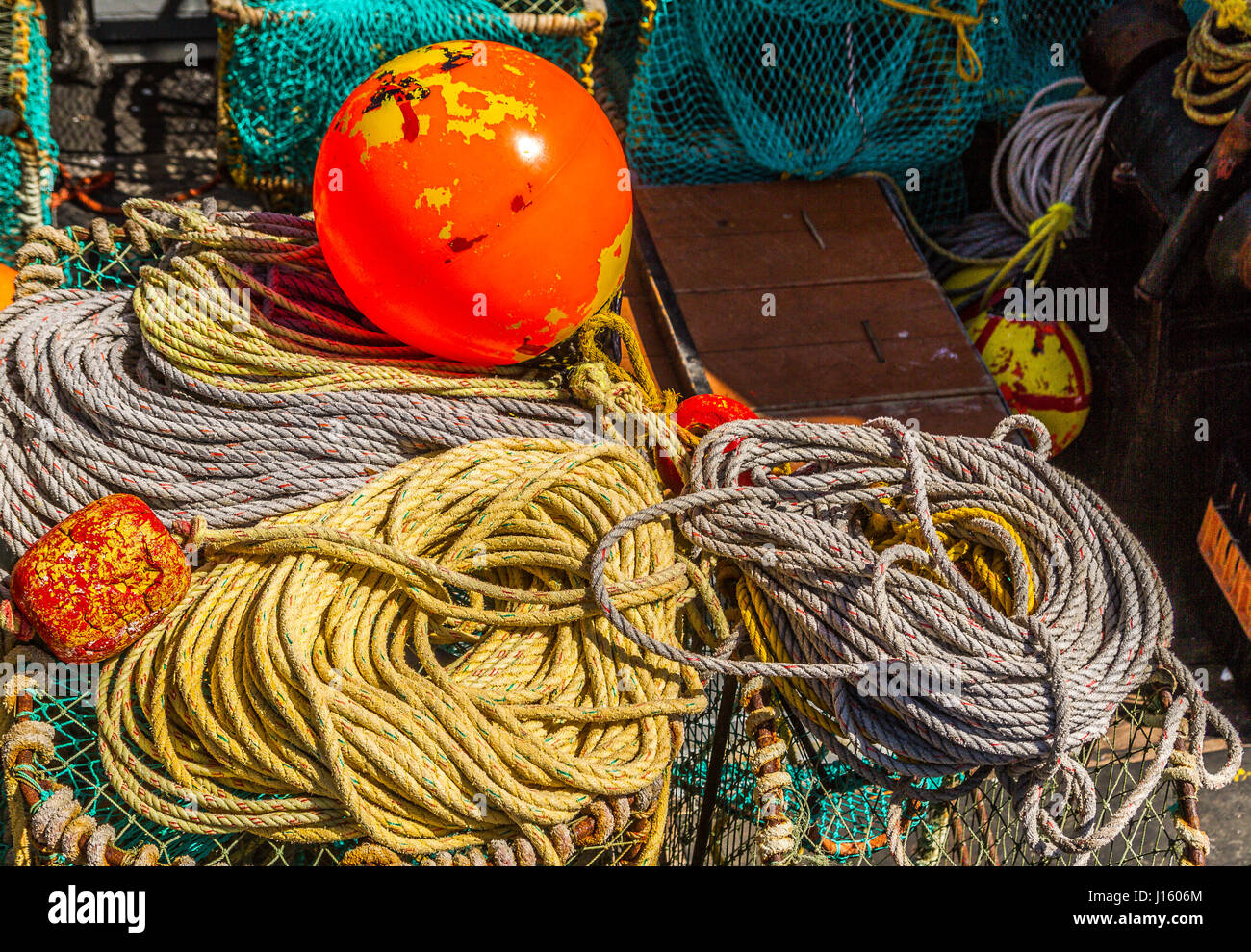 Coils of rope ropes and an orange marker buoy on the floor of a fishing boat in Hout Bay ,South Africa Stock Photo