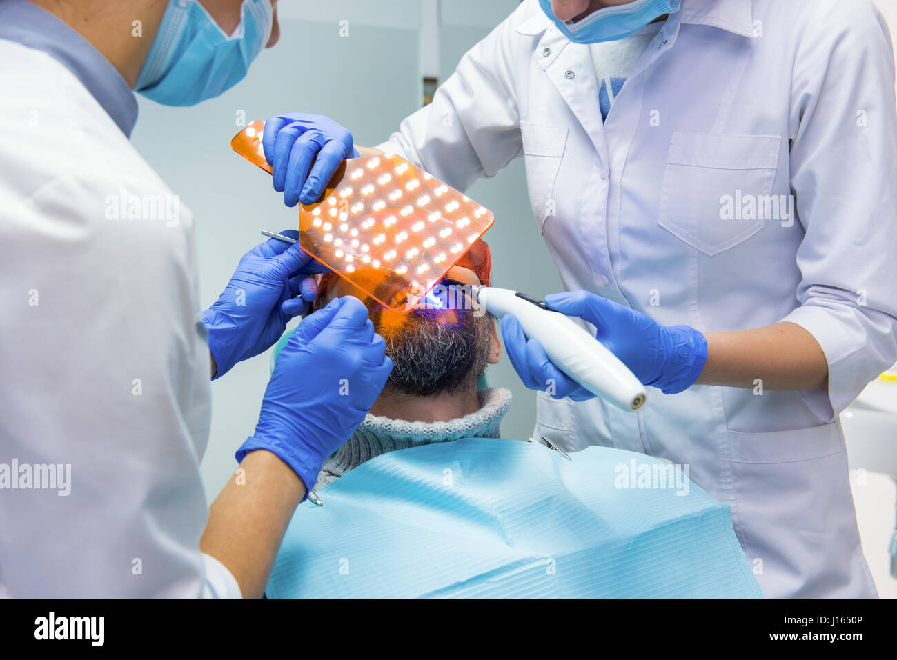 Two dentists at work. Stomatologist using UV light. Knowledge, skills