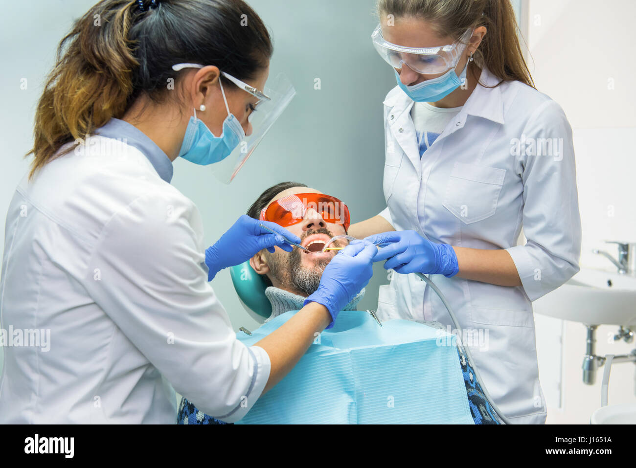 Two female dentists at work. Dental patient in protective glasses Stock