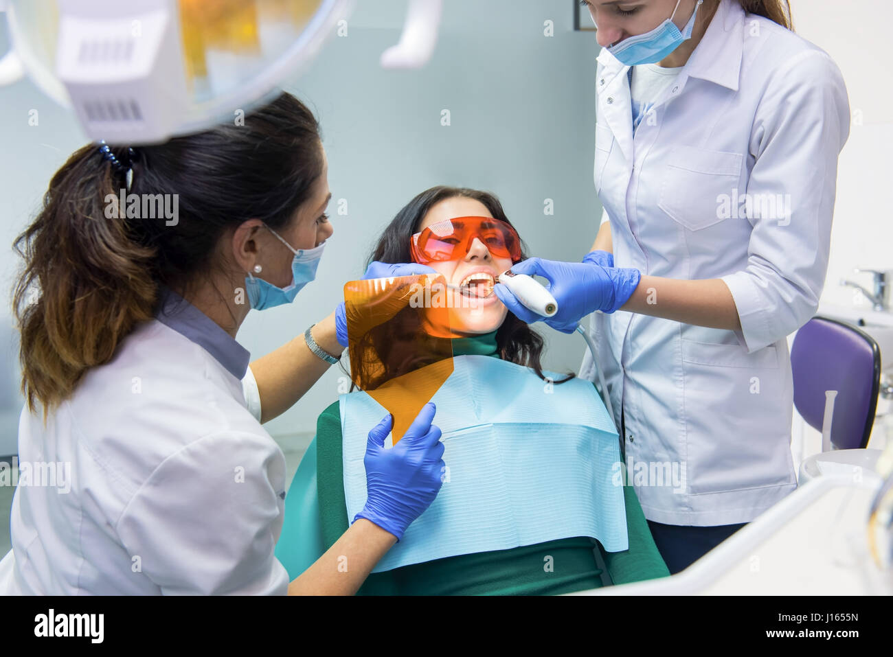 Doctor using dental curing light. Two stomatologists working with