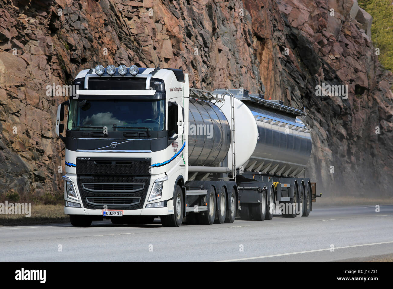 KARJAA, FINLAND - APRIL 10, 2016: New, white Volvo FH tank truck on moves along highway, with rock face on the background. Stock Photo