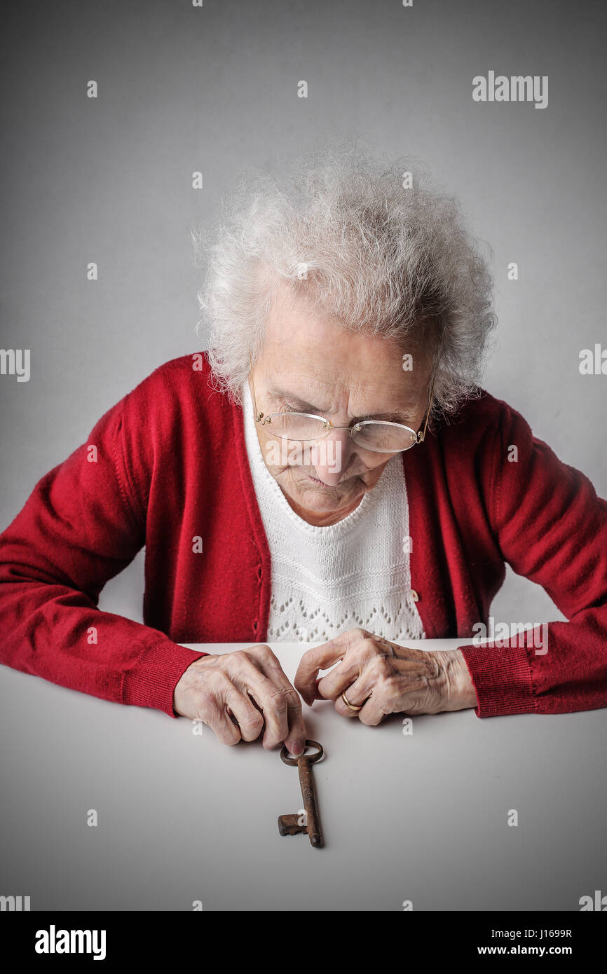 Old lady looking at key Stock Photo