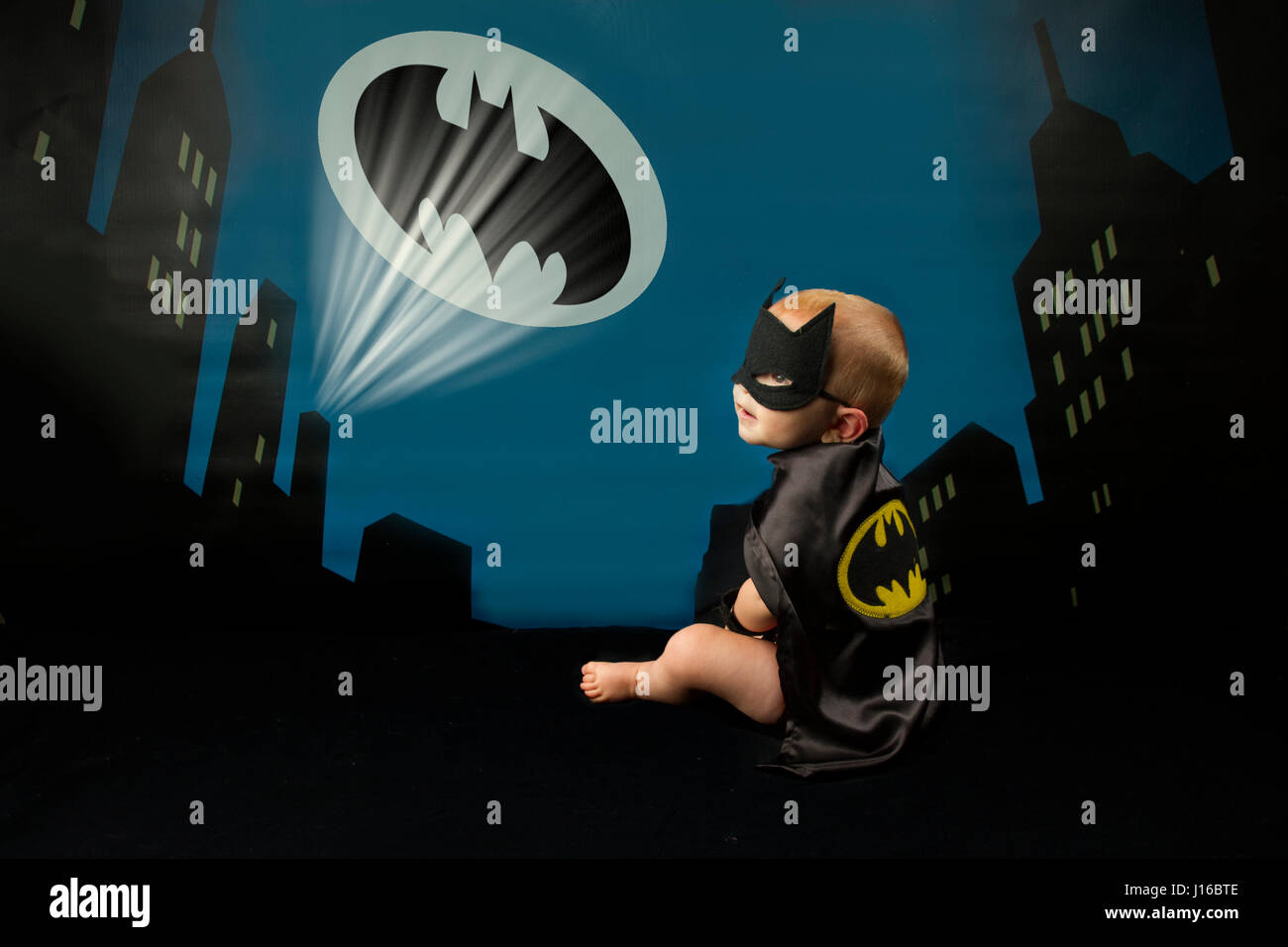 WASHINGTON STATE, USA: Baby Batman gazes up at the Bat Signal. IS IT A BIRD? Is it a plane? No, it’s a pint-sized Superman. From flying faster than a speeding bullet like Superman to web-slinging like your friendly neighbourhood Spiderman these cute baby pictures show mini-superheroes in all their glory. Complete with perfectly created capes, masks and superhero symbols the heart-melting shots of Batman, Batgirl, Superman, Captain America and Wonder Woman showcase the classic superheroes from DC and Marvel comics in the tiny form of babies. Superhero-fan and baby photographer Christy Peterson  Stock Photo