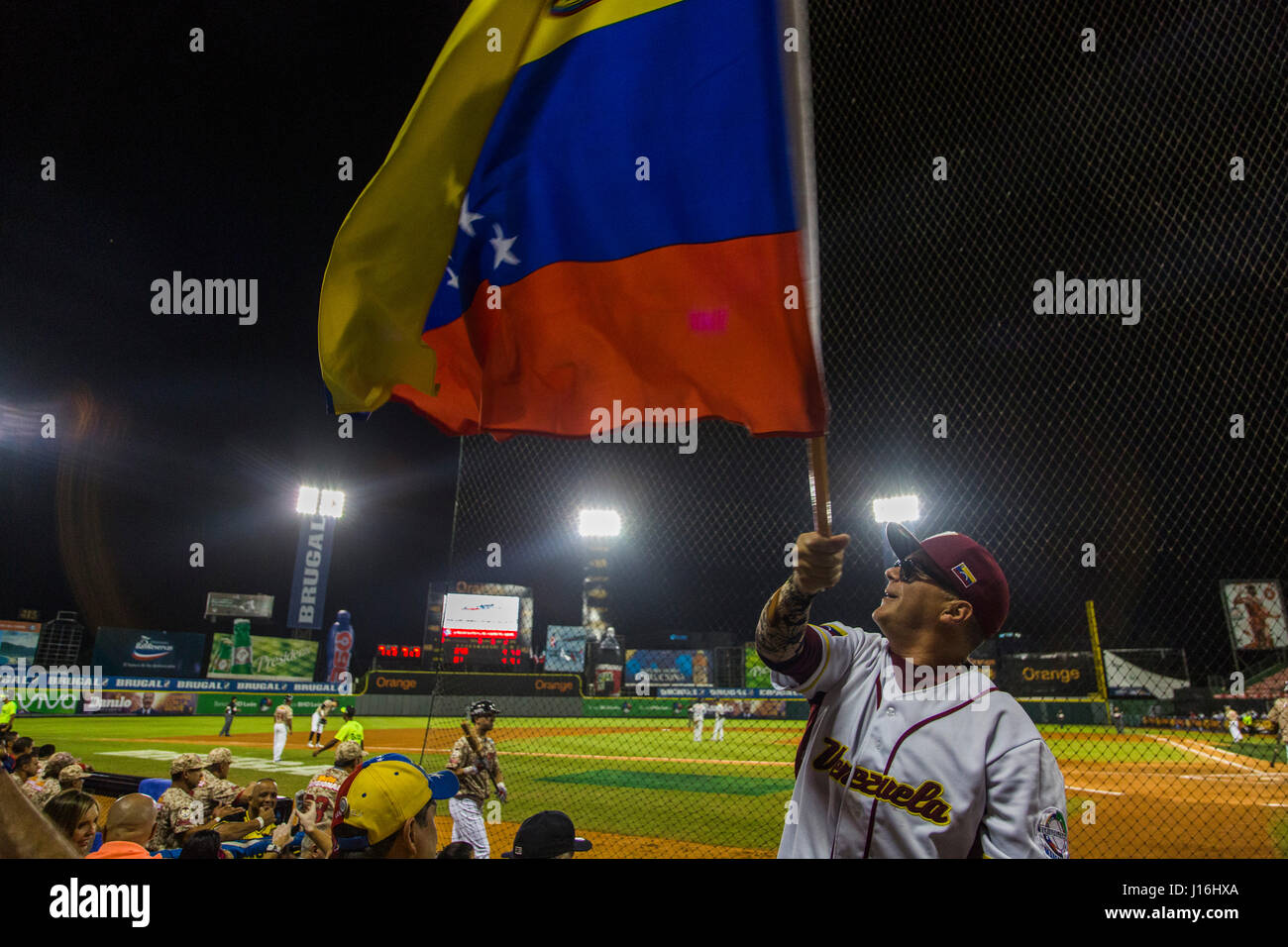 A Baseball Fan Waves A Large Venezuelan Flag In A Stadium Under A The Lights In The Dominican Republic Stock Photo