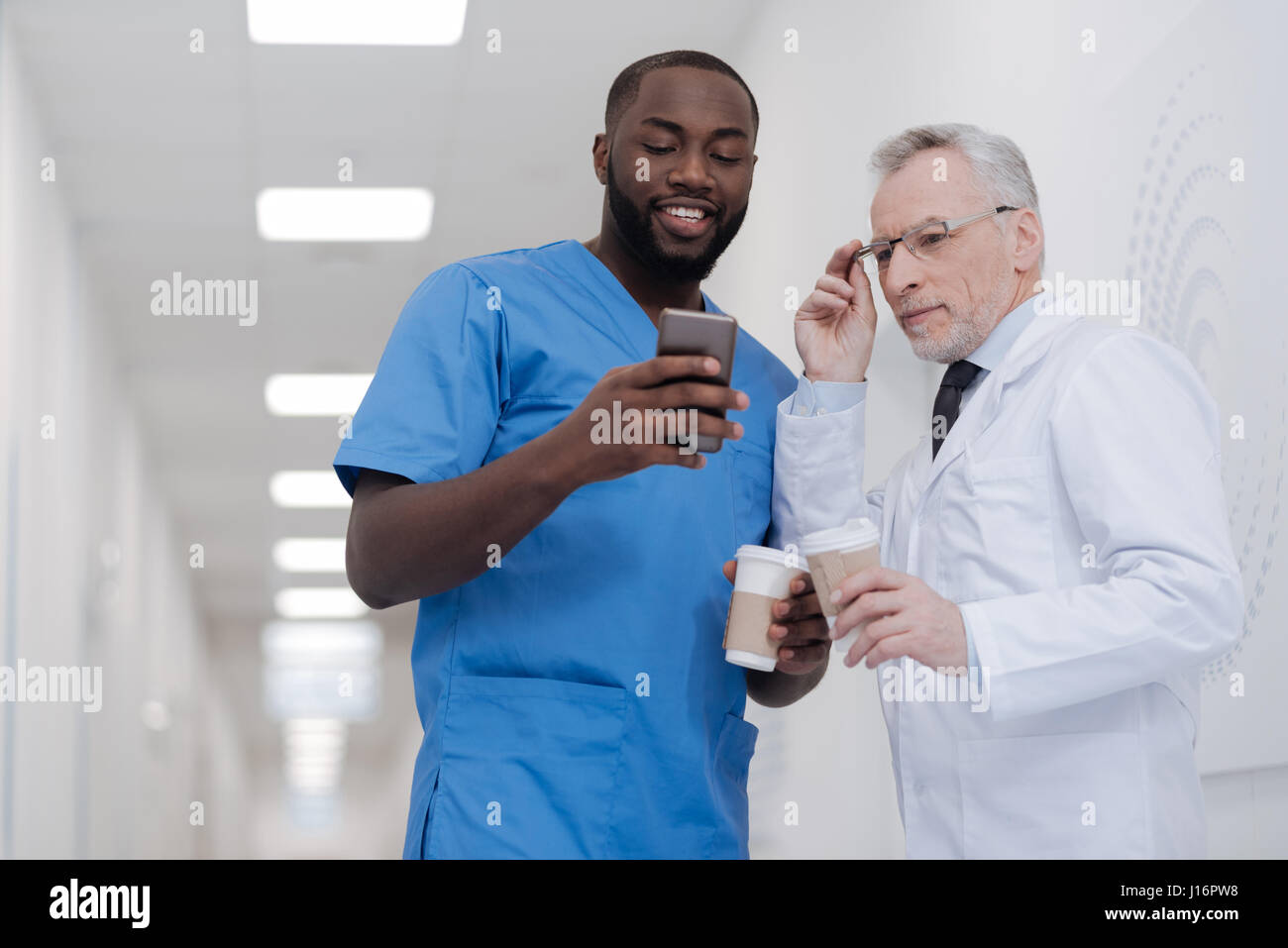 Sociable African American intern sharing news with senior colleague Stock Photo