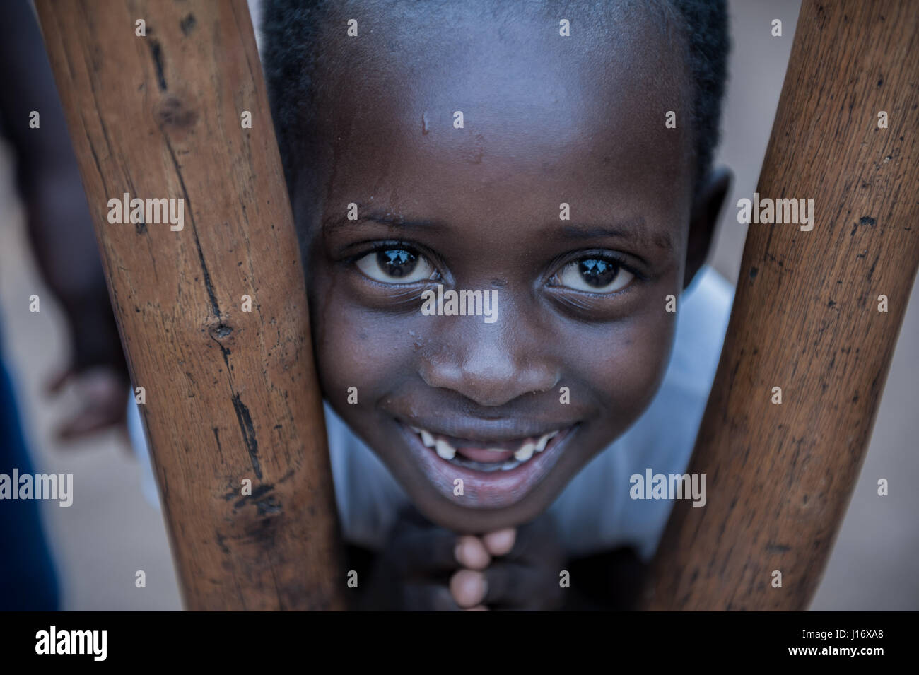 A child looking through the poles of a mortar and pestle in Dungu, north east Democratic Republic of Congo Stock Photo