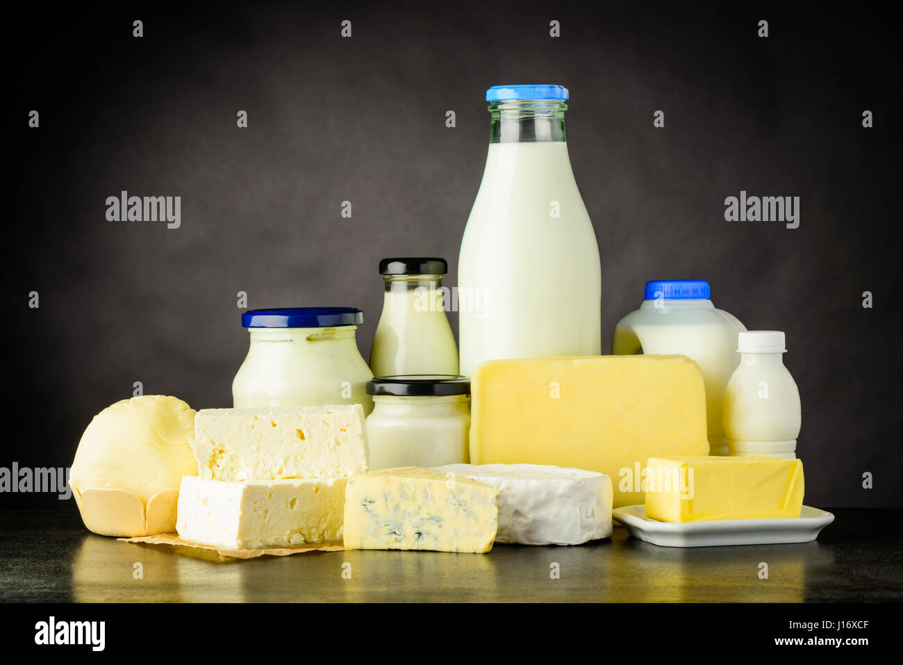 Different Types of Dairy Products with Milk, yoghurt and Cheese in Bottles and Jar on Dark