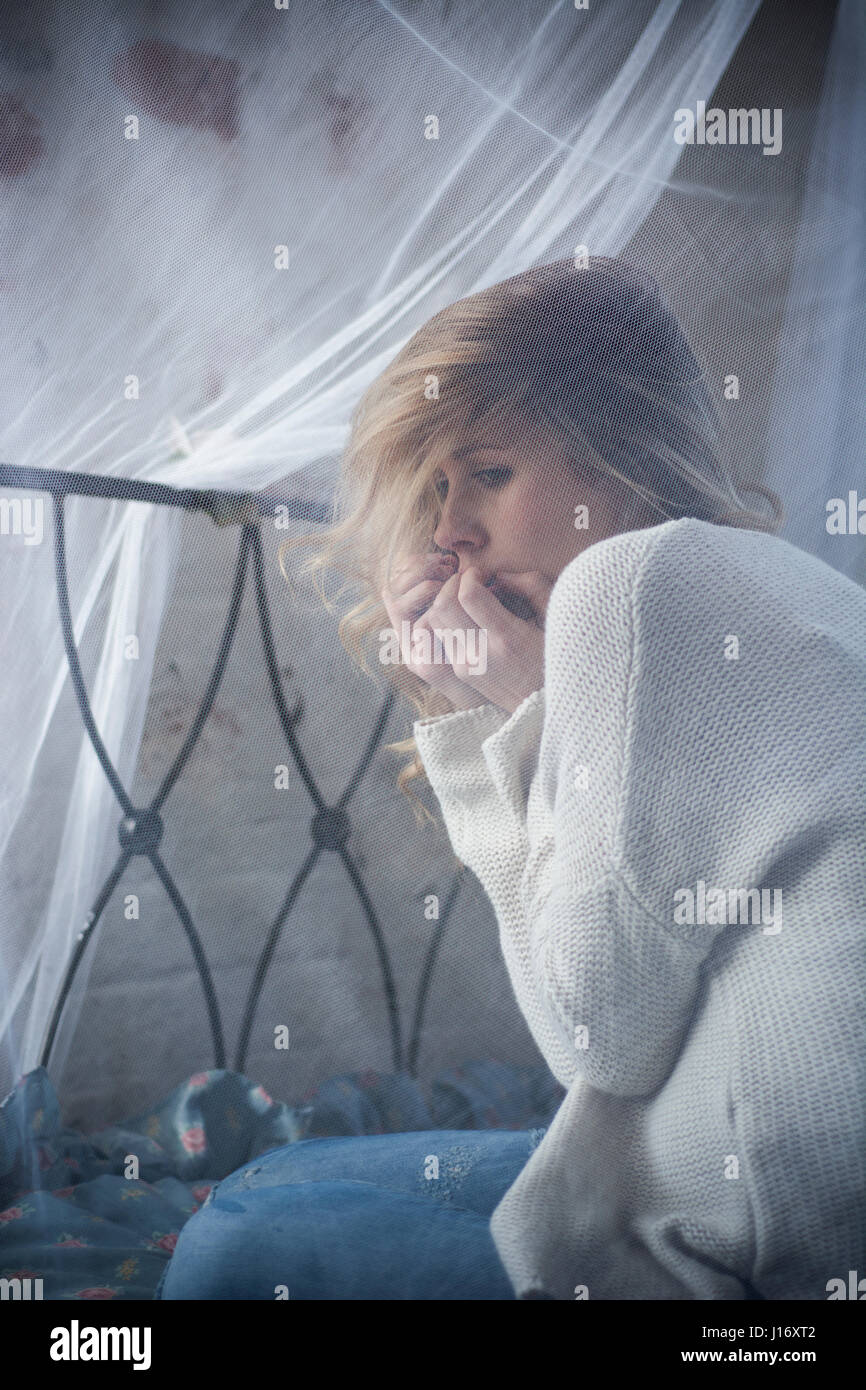 Young blond woman hiding face in hands crying in fear Stock Photo