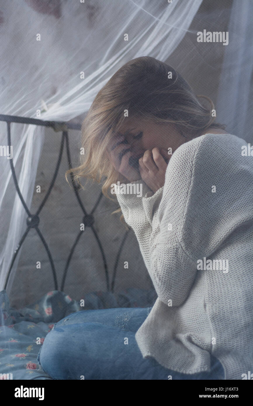 Young blond woman hiding face in hands crying in fear Stock Photo