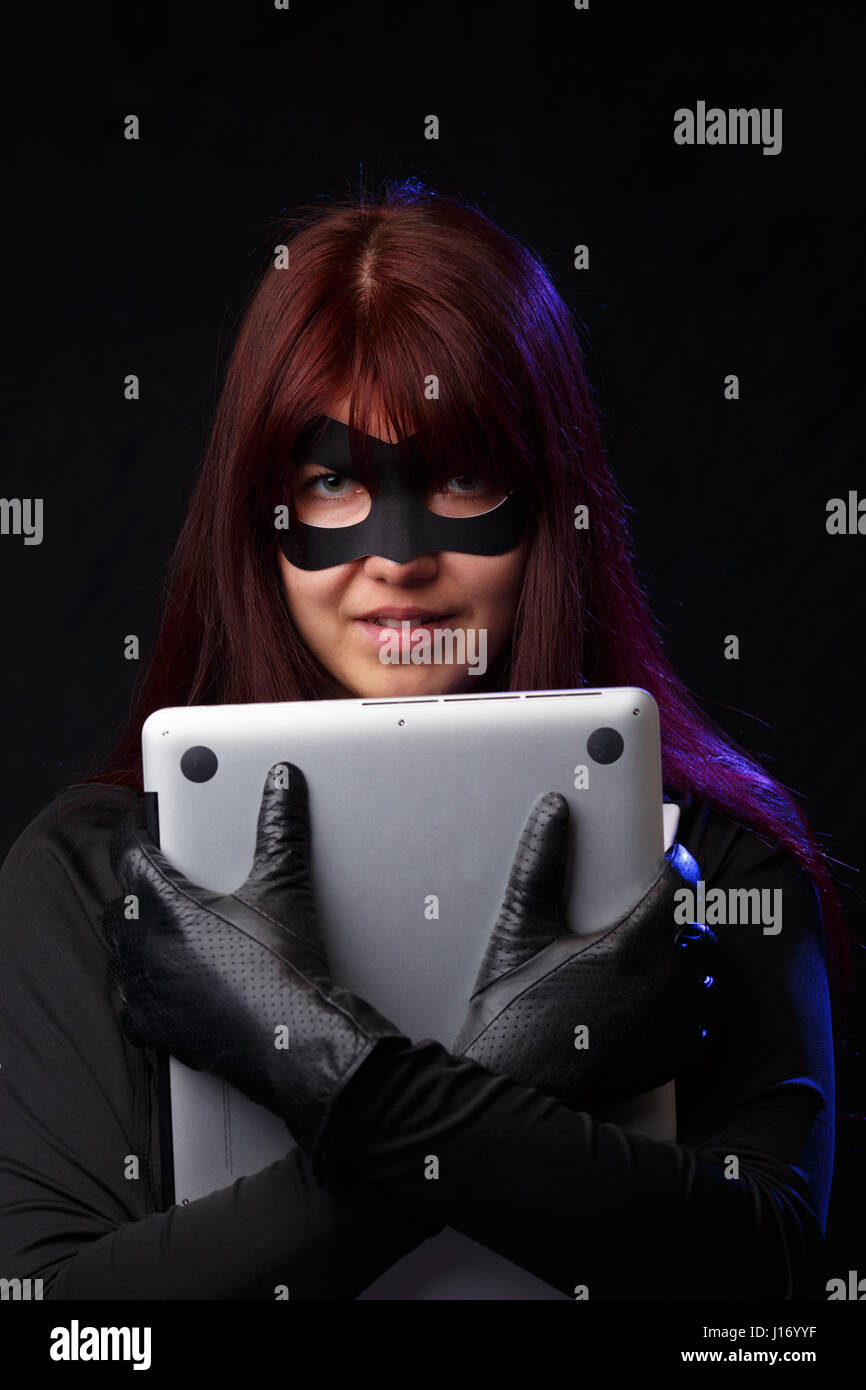 Brunette hacker cuddle stolen laptop Stock Photo