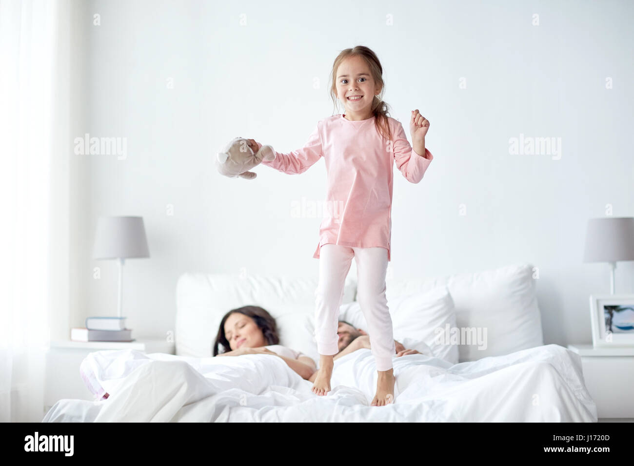 happy child with toy and parents in bed at home Stock Photo