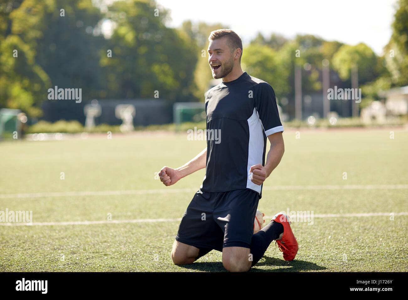 happy soccer player with ball on football field Stock Photo