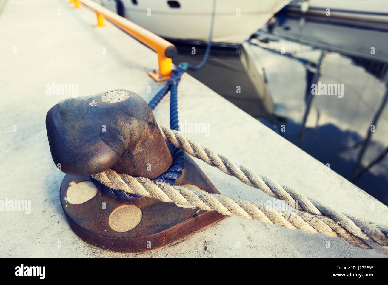 rusted iron mooring bollard with rope on pier Stock Photo