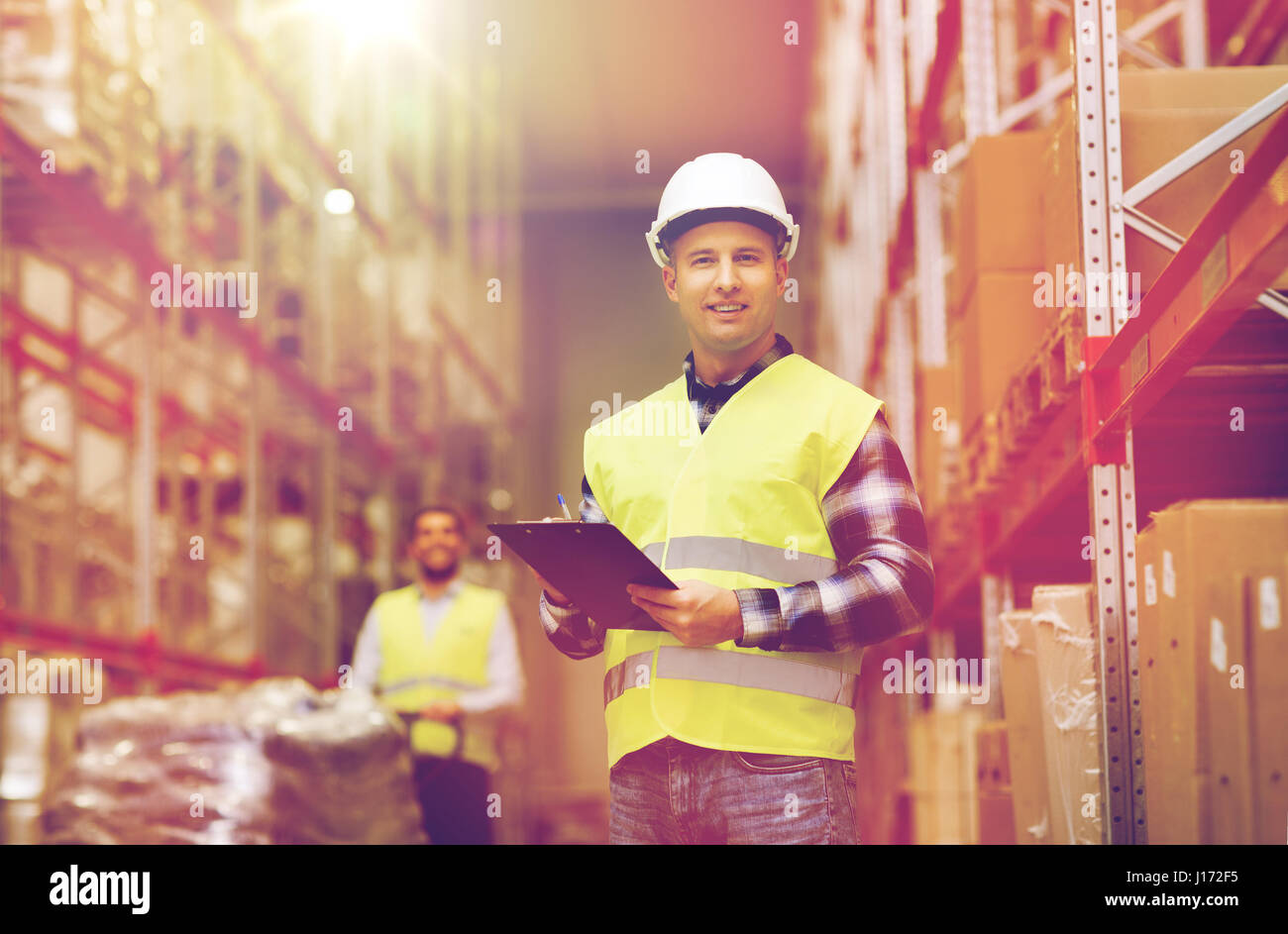man with clipboard in safety vest at warehouse Stock Photo
