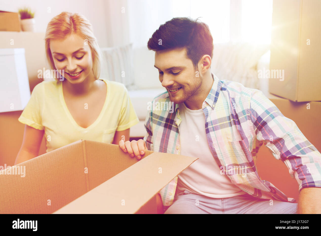 smiling couple with big boxes moving to new home Stock Photo - Alamy