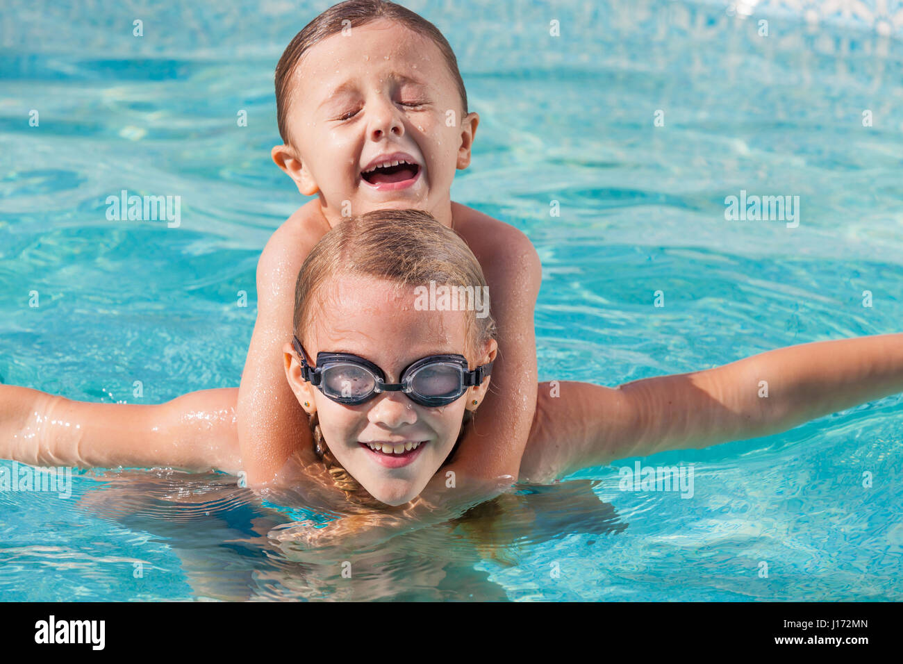 Two happy children playing on the swimming pool at the day time. People having fun outdoors. Concept of friendly siblings. Stock Photo