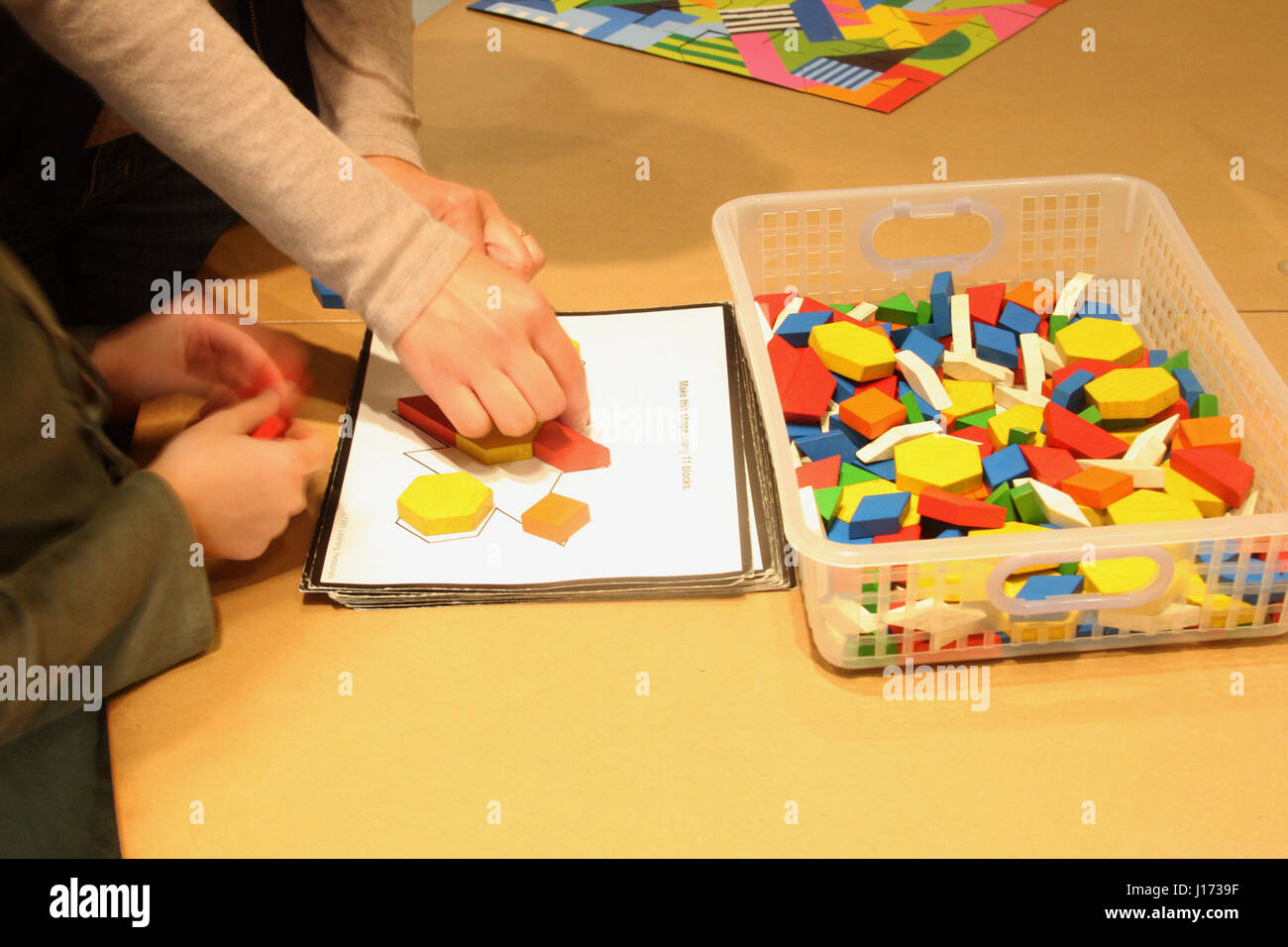 Little kid and adult working on a puzzle of geometrical shapes Stock Photo
