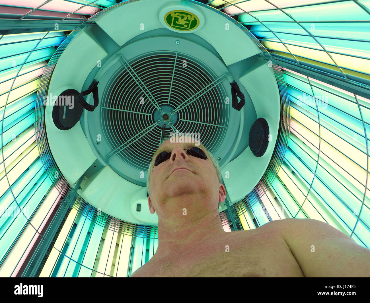 Man in a stand up UV tanning booth Stock Photo