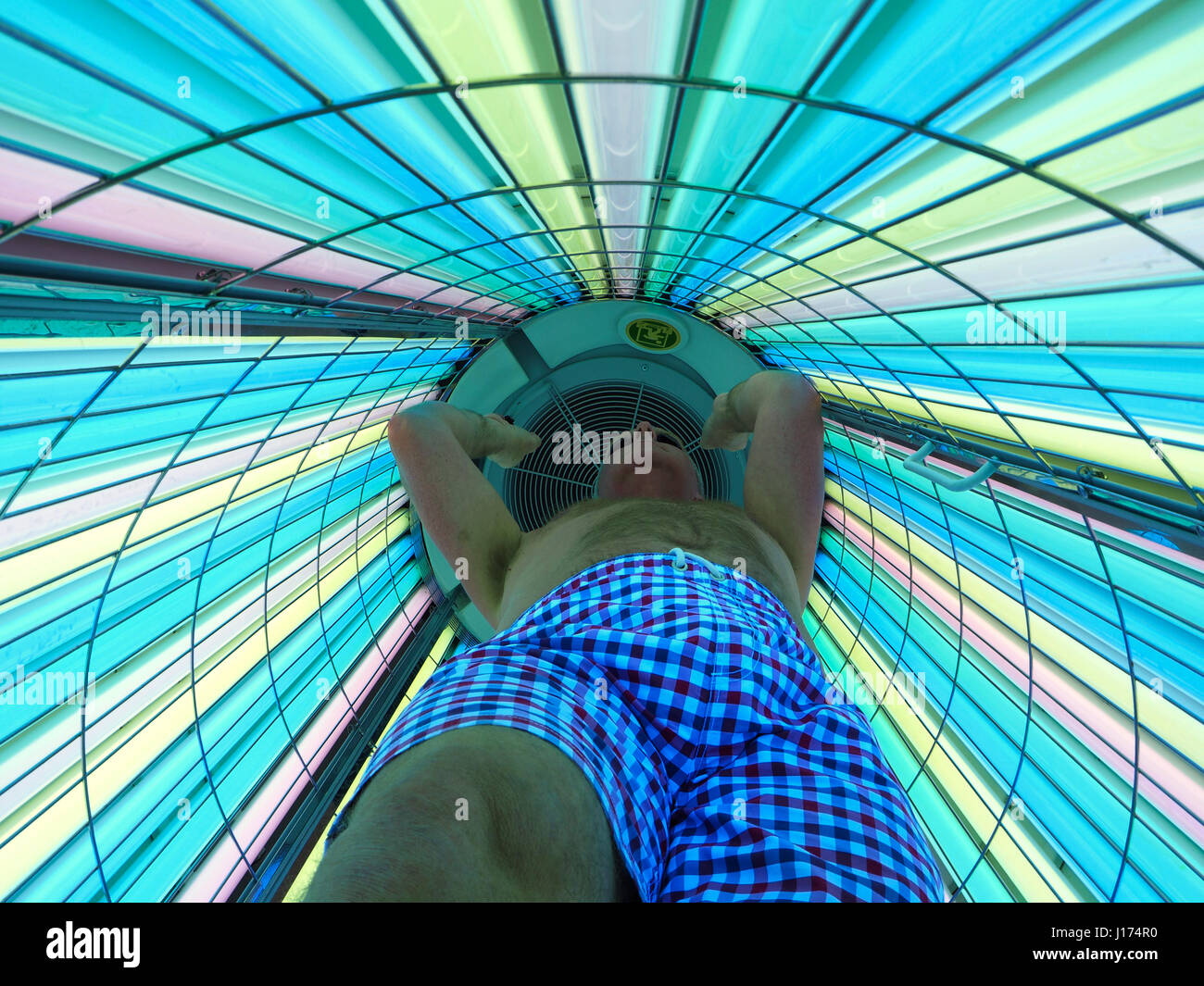 Man in a stand up UV tanning booth Stock Photo