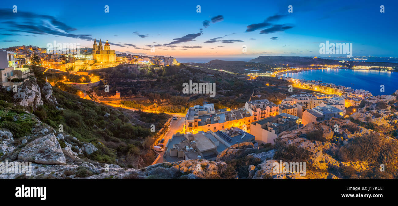 Il-Mellieha, Malta - Beautiful panoramic skyline view of Mellieha town after sunset with Paris Church and Mellieha beach at background with blue sky a Stock Photo