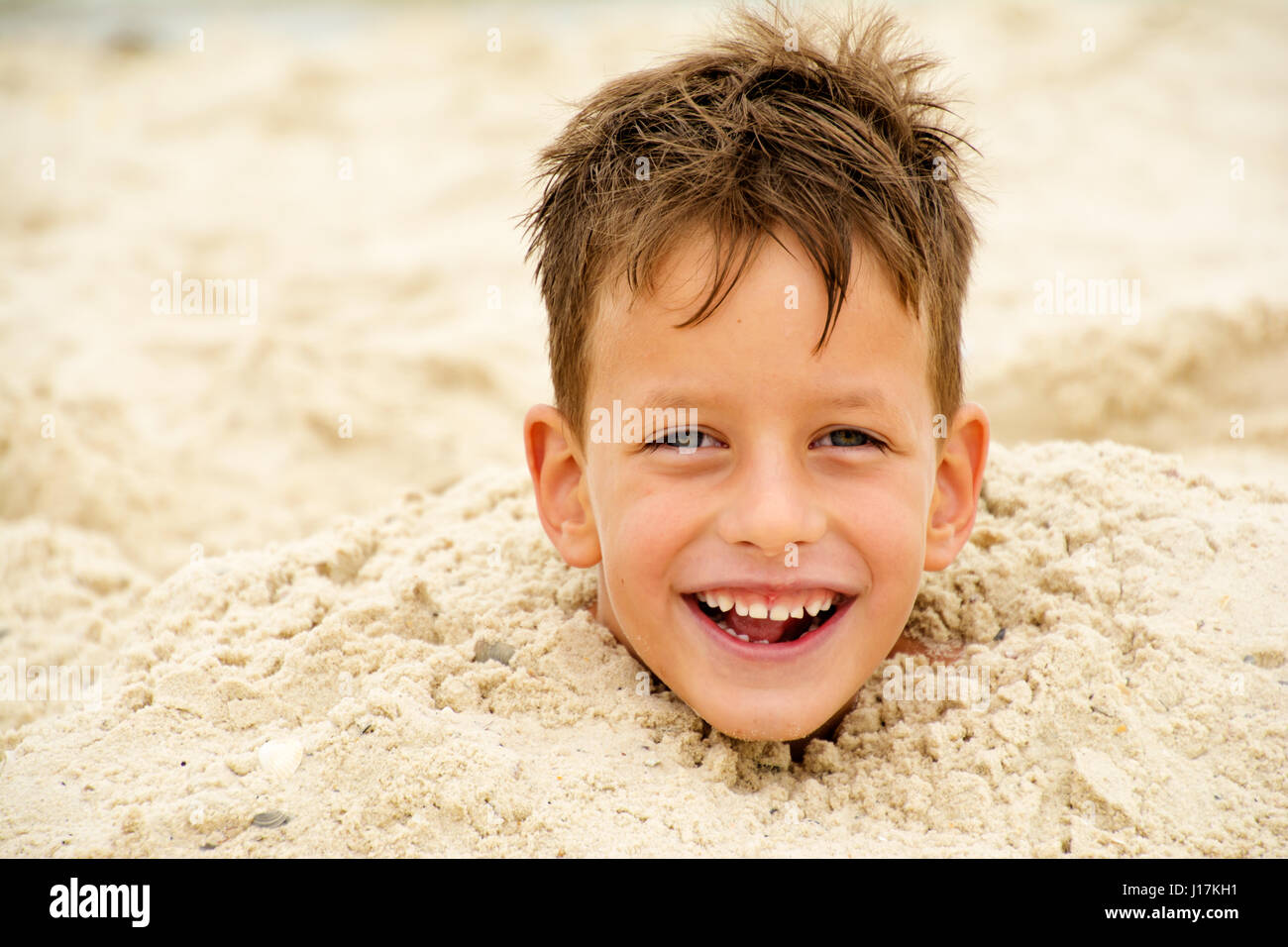 head of a boy buried in the sand Stock Photo Alamy