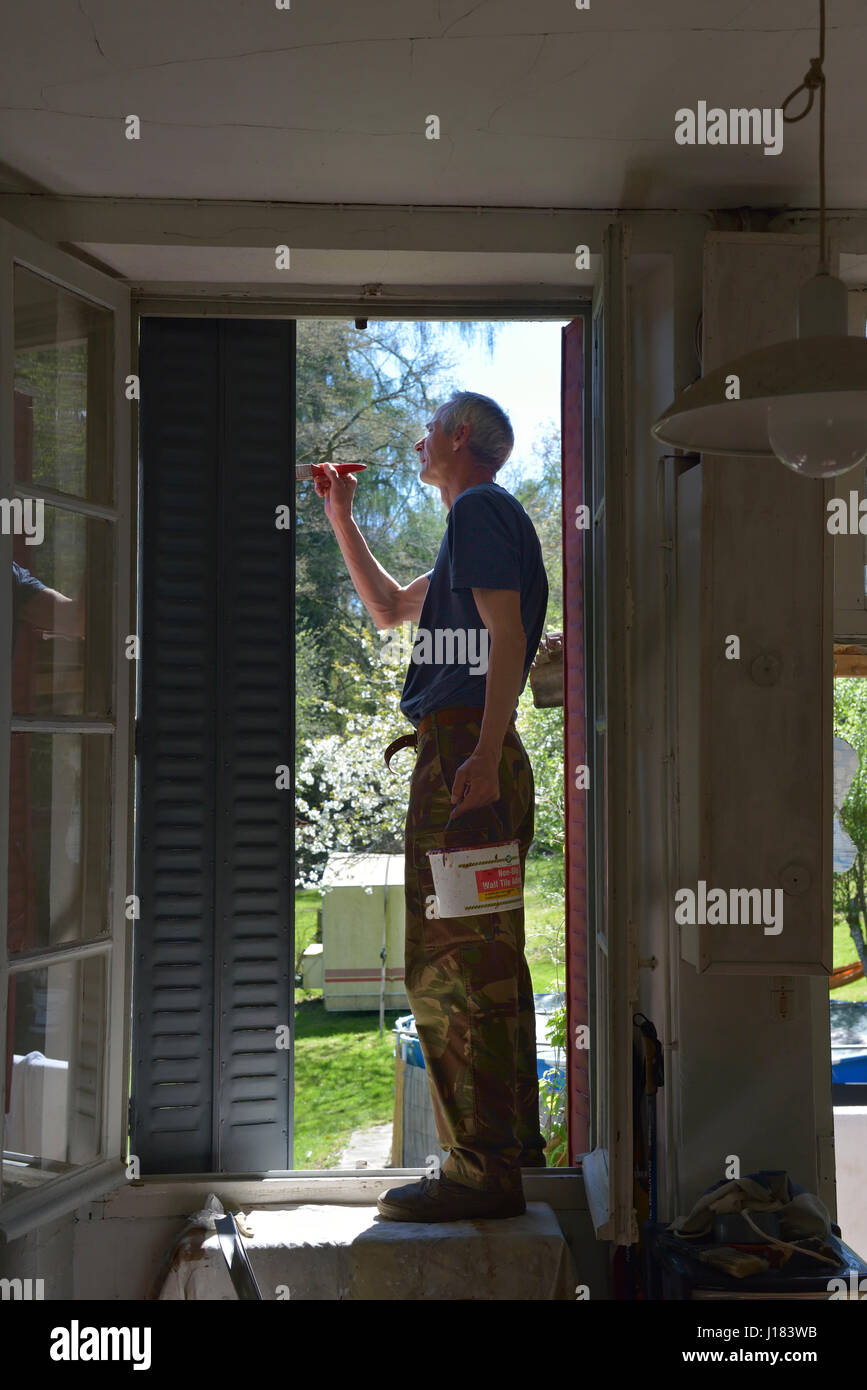 Painter and decorator painting  window shutters, England, UK Stock Photo
