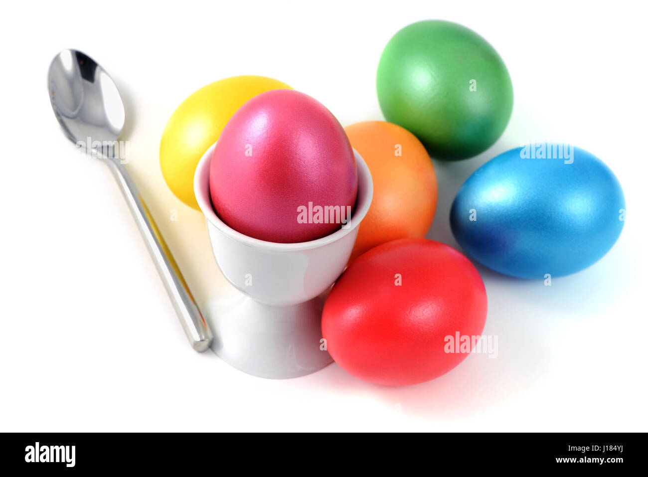 Cup with easter eggs and spoon on white isolated background Stock Photo