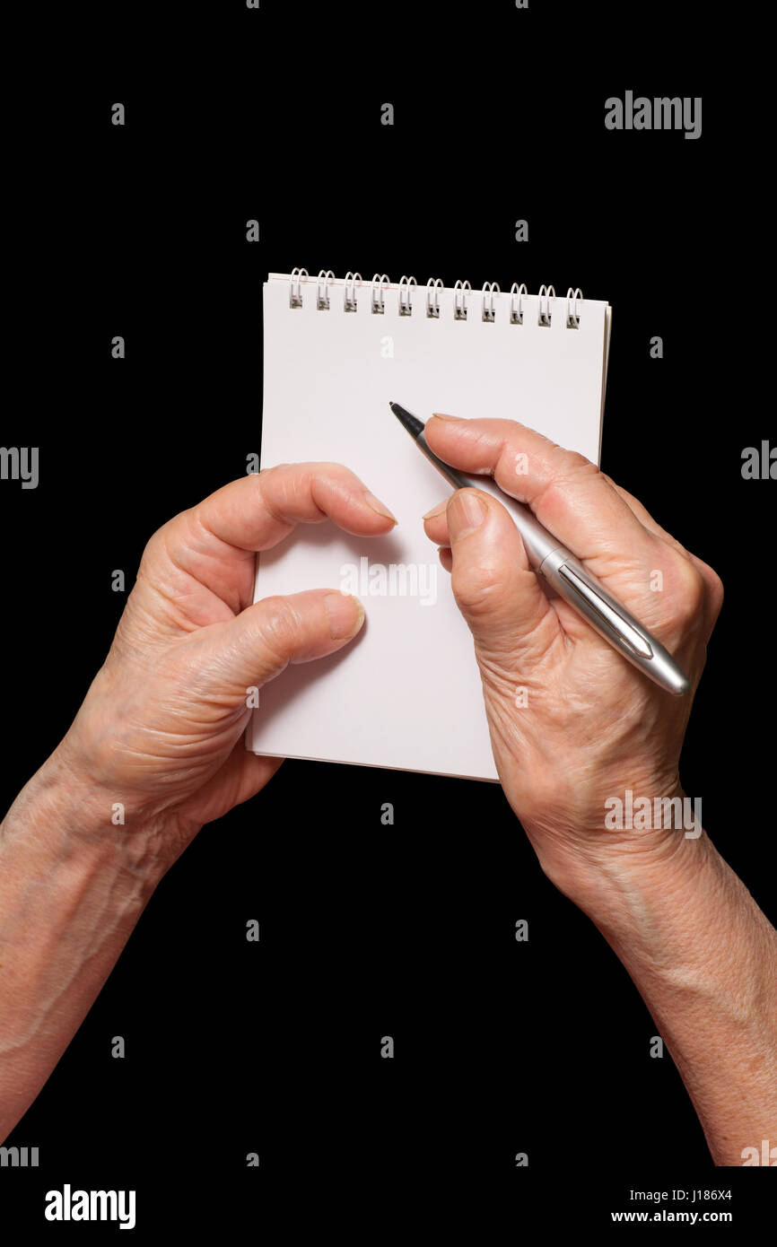 Senior woman hands with pen and blank notebook. Old person writing, calculating or making notes  theme. Isolated on black, clipping path included. Stock Photo