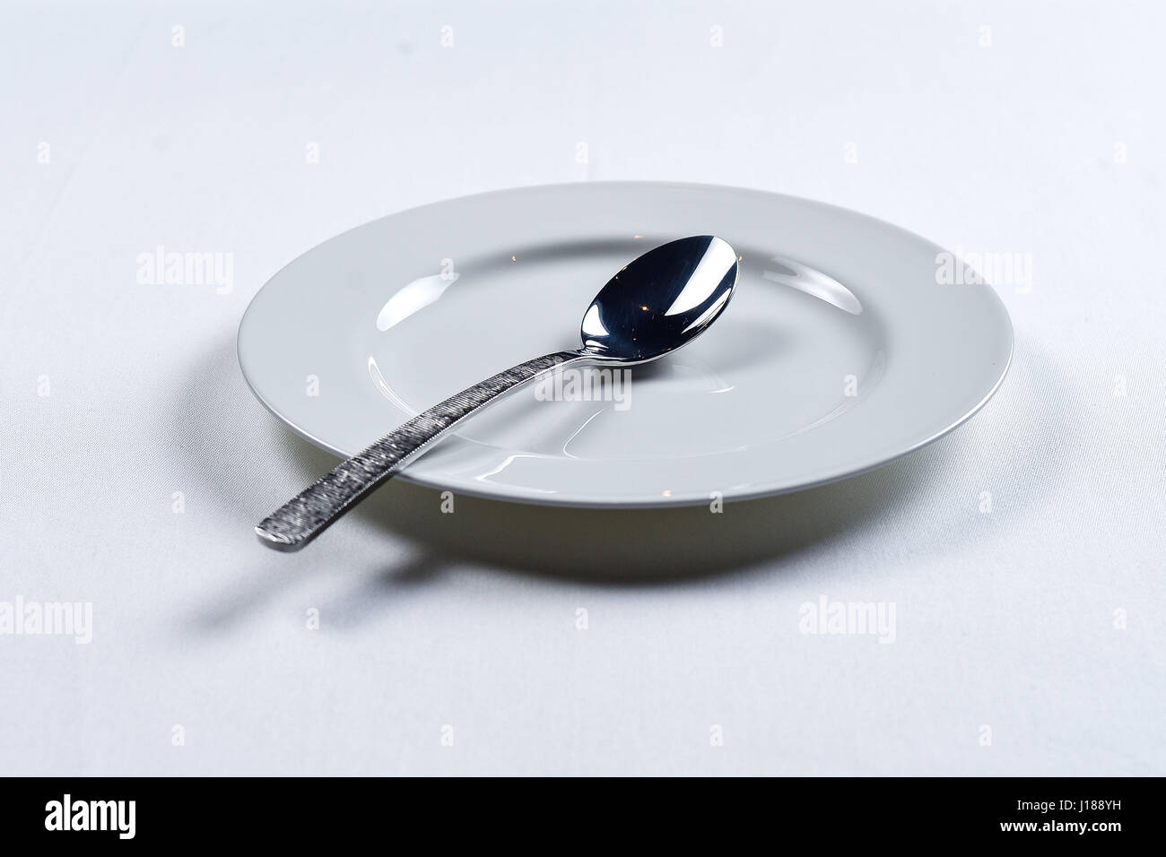 white plate with a knife and fork on a white background Stock Photo - Alamy