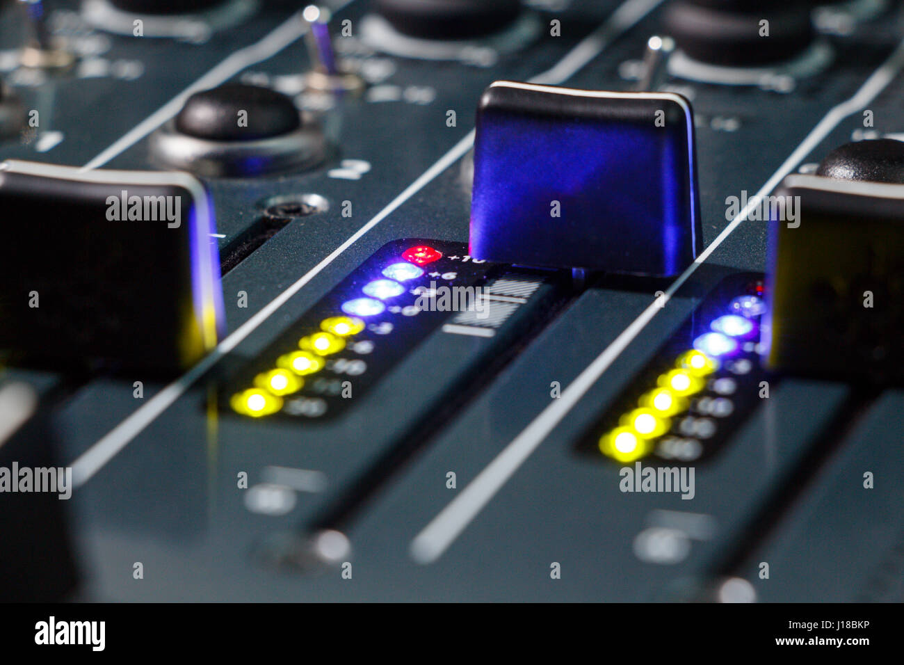 Close up shot of a DJ mixer volume faders with volume levels in the red Stock Photo Alamy