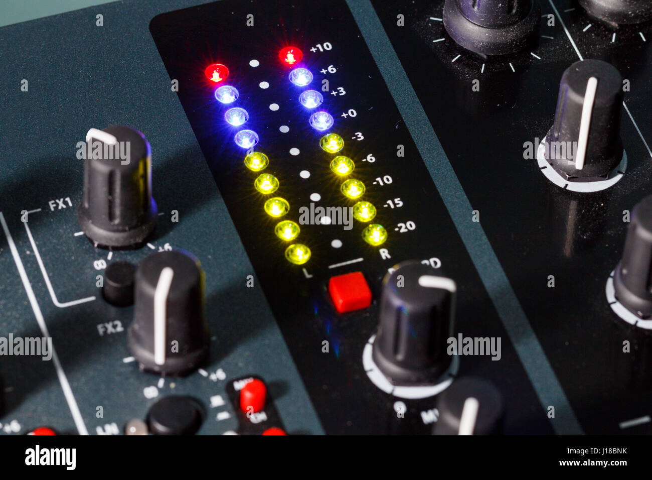 Close up shot of a DJ mixer volume faders with volume levels in the red