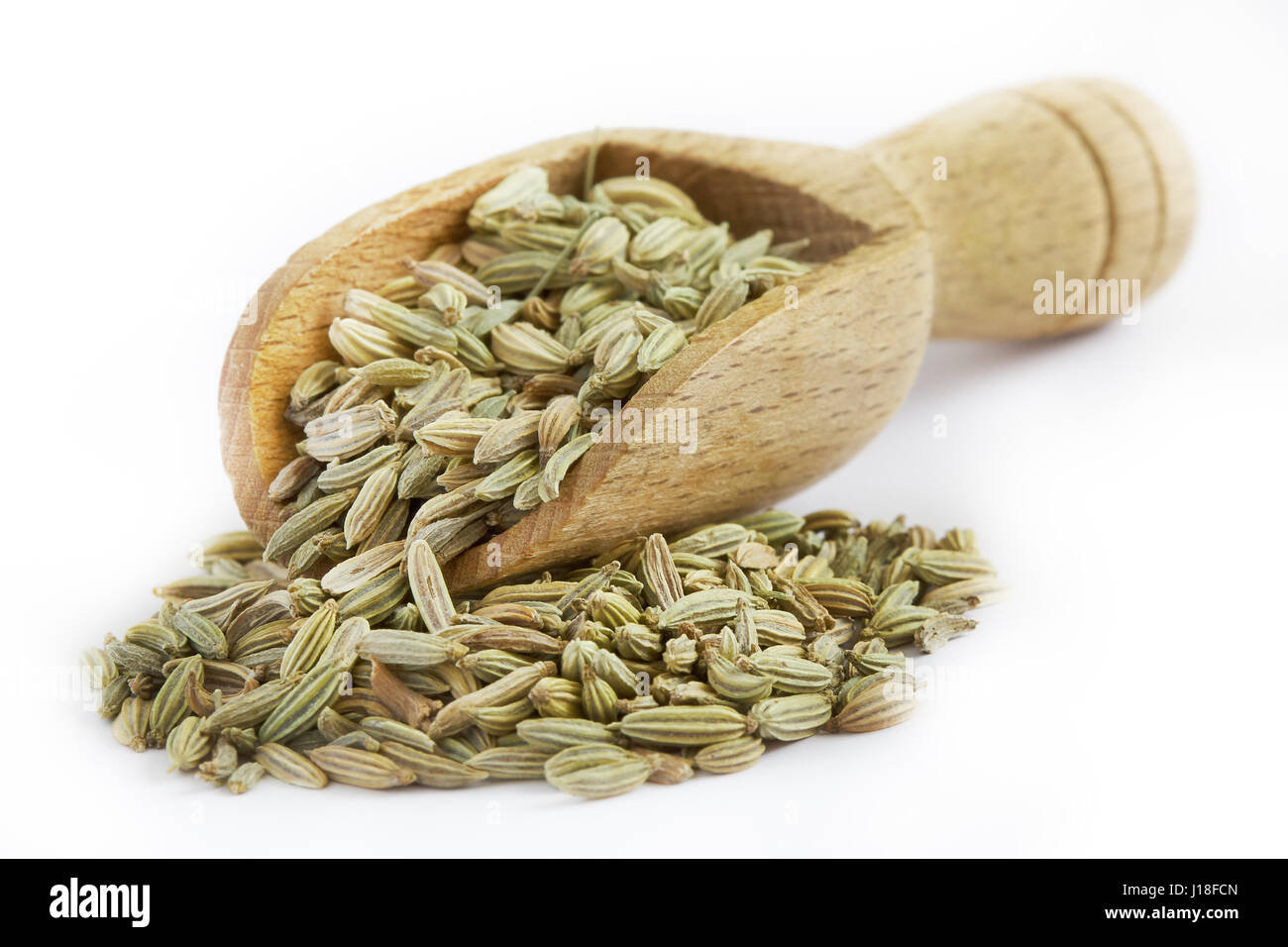 Dried fennel seeds in wooden scoop isolated on white background Stock