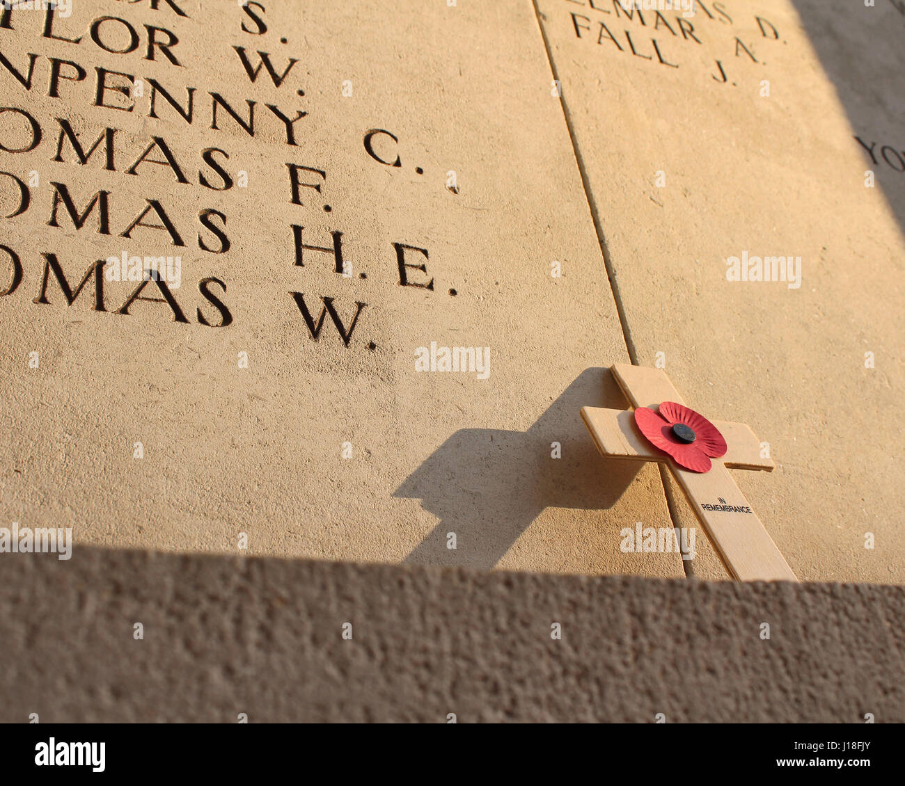 A poppy memorial cross left poignantly at the Menin Gate in Ypres, lit by a low evening sun. Stock Photo