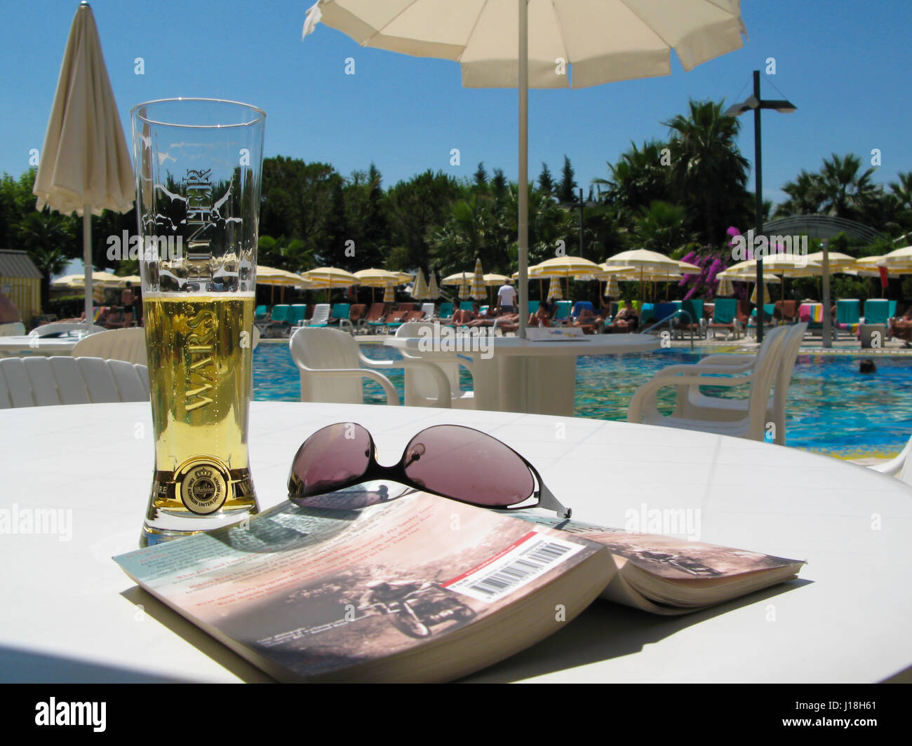poolside view of a beer, a book and sunglasses Stock Photo Alamy