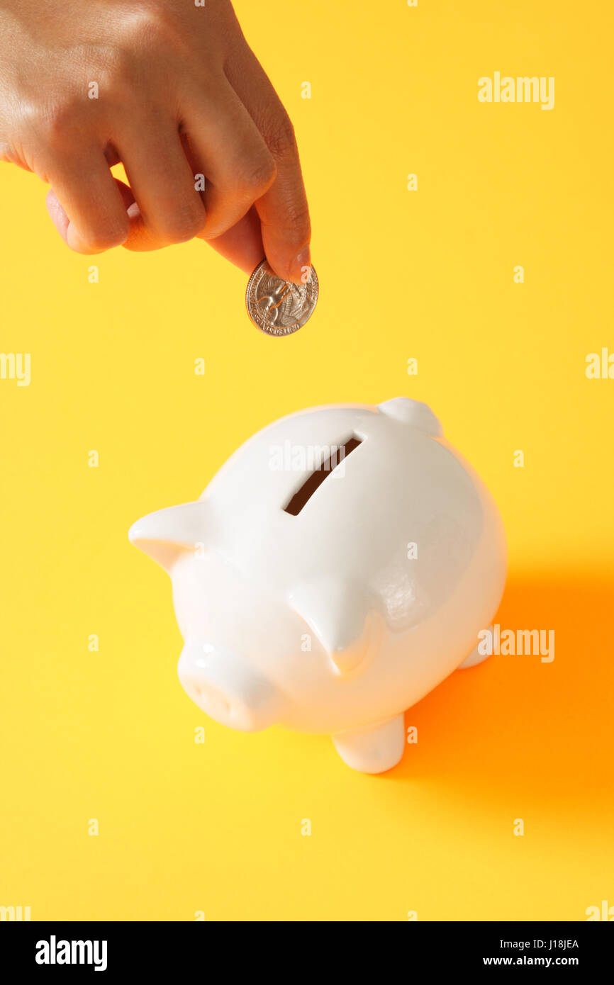 A woman saving a coin into a piggy bank Stock Photo - Alamy