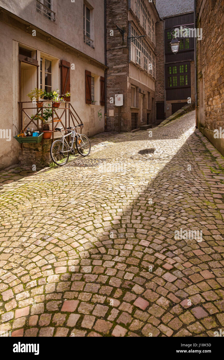 A back street in Saint Malo, Brittany, France, with a beam of sunlight lighting the cobbles. Stock Photo