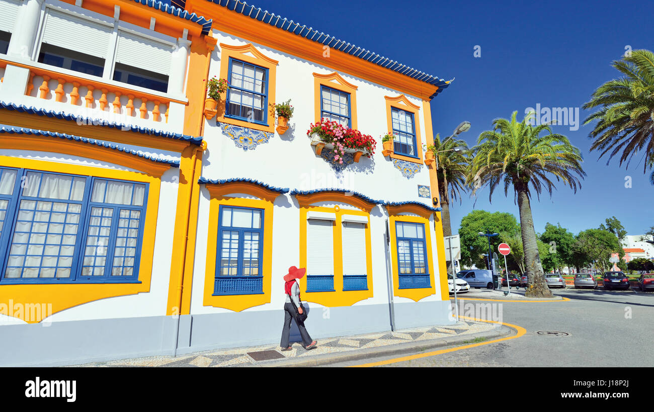 Woman with red hat crossing colorful house with ornamented windows Stock Photo